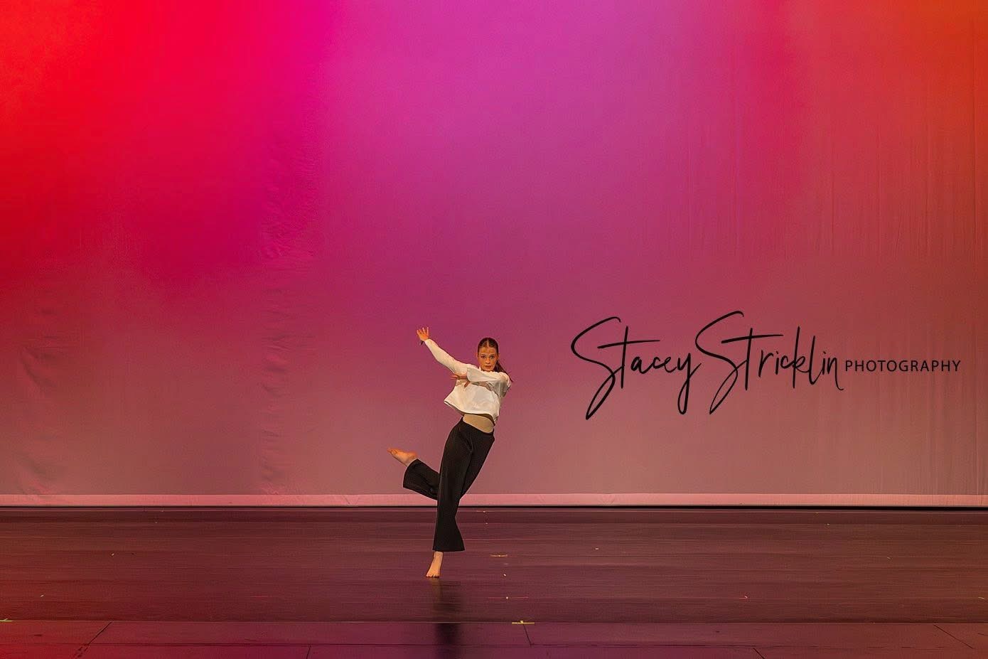 Contemporary dancer moving across a pink-lit stage