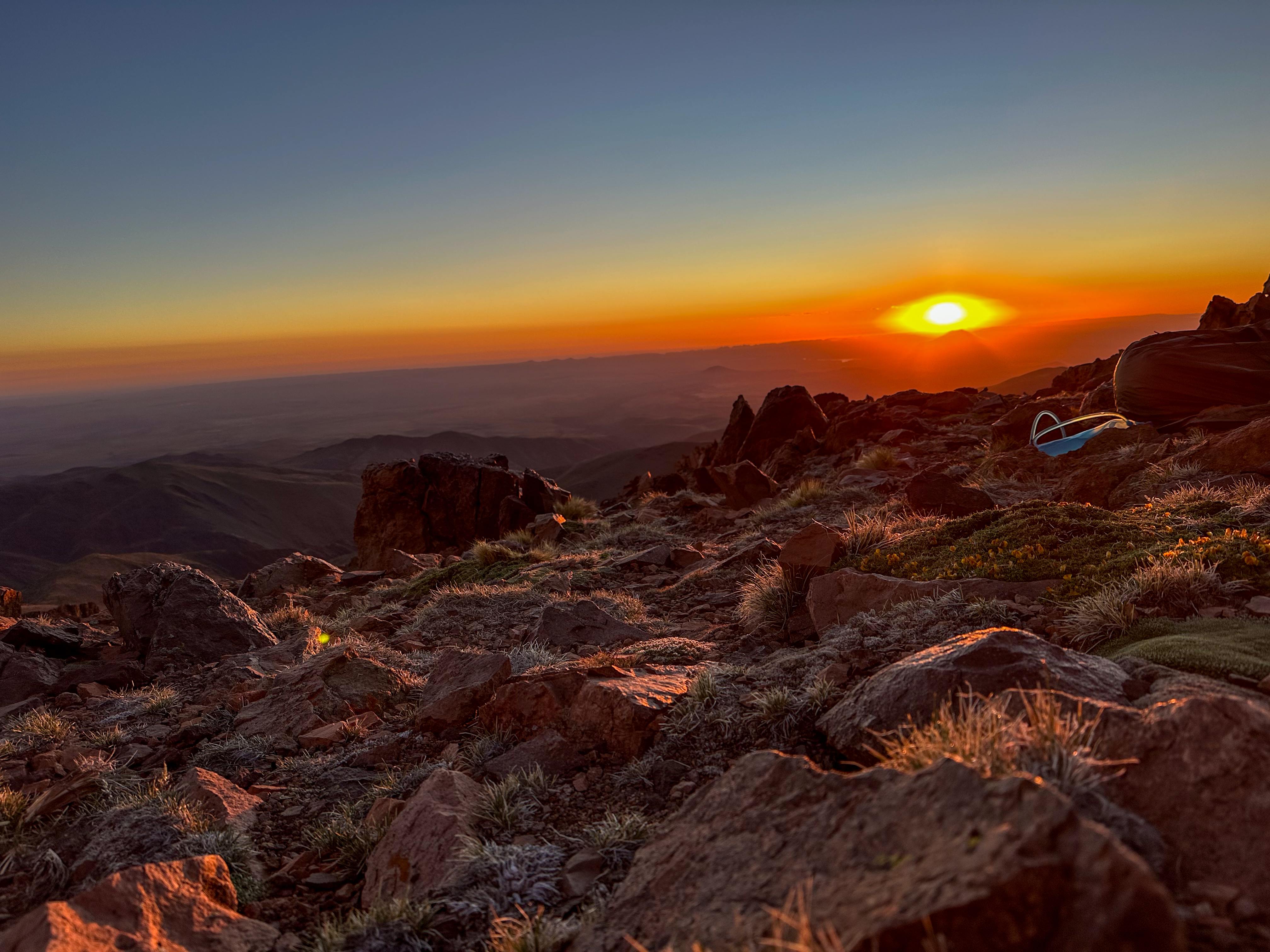 Amanecer espectacular desde cumbre de montaña con carpa