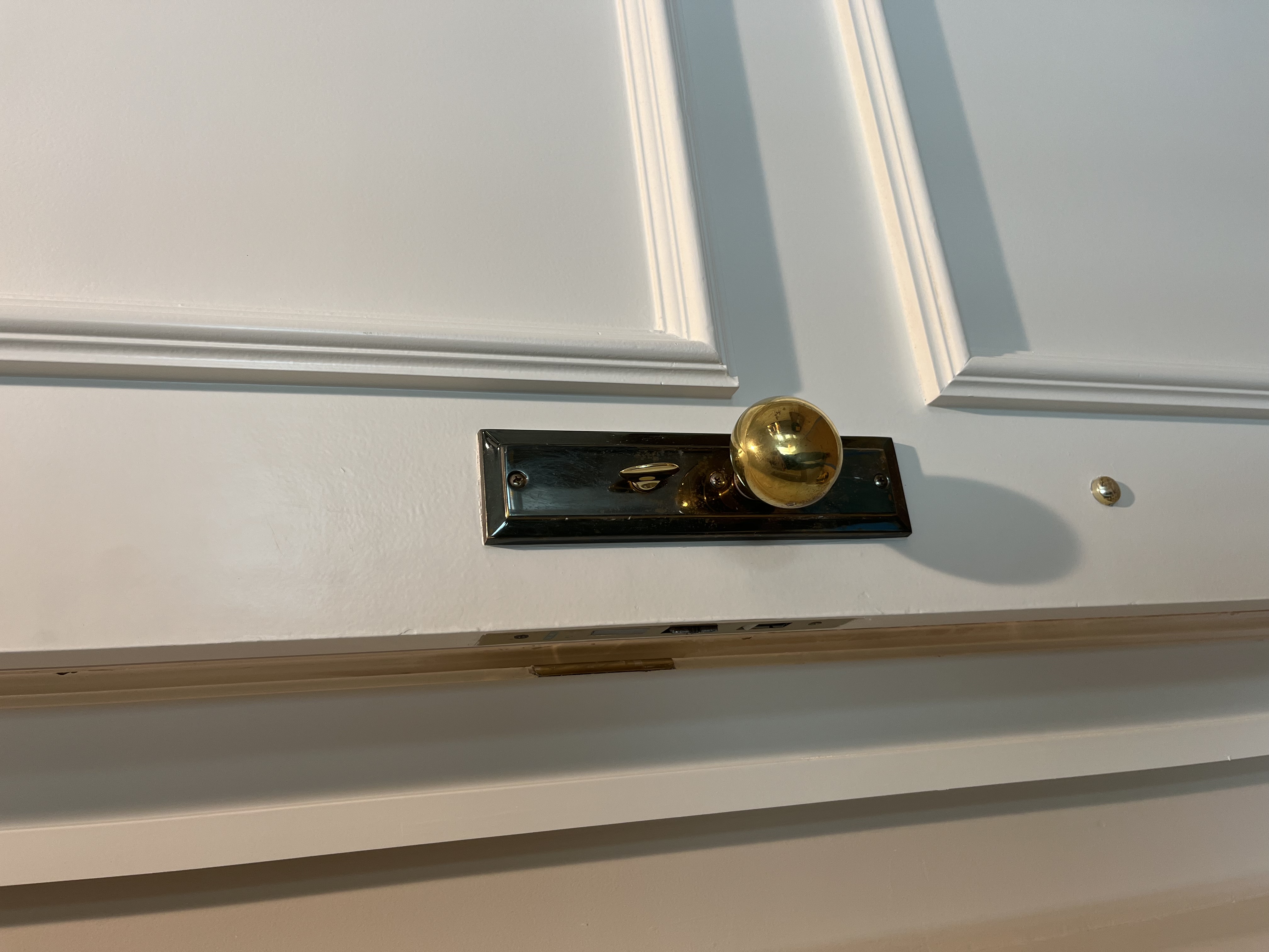 Before: original failing mortise lock with tarnished brass backplate and ball knob