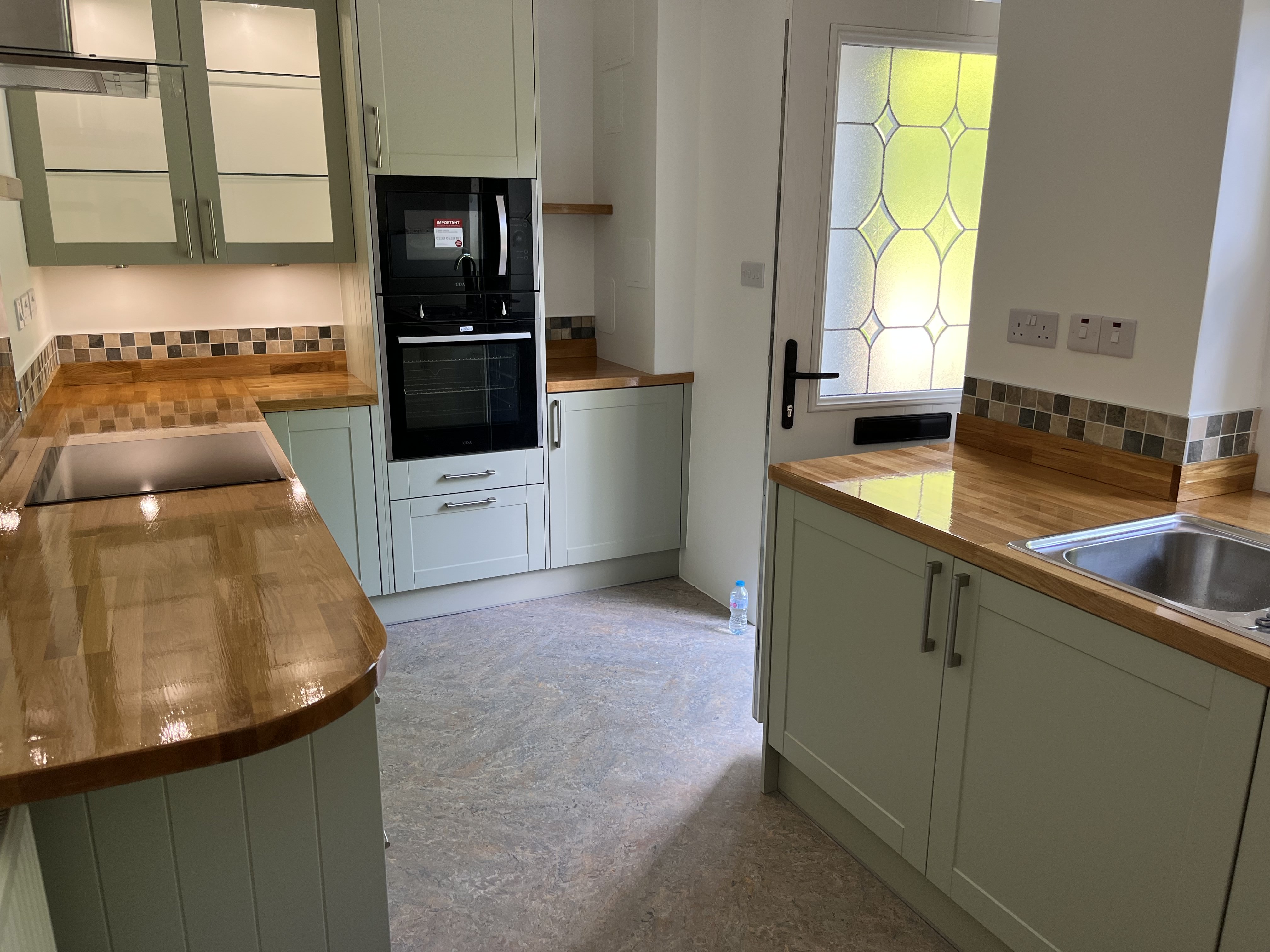 Completed sage green shaker kitchen with oak worktops