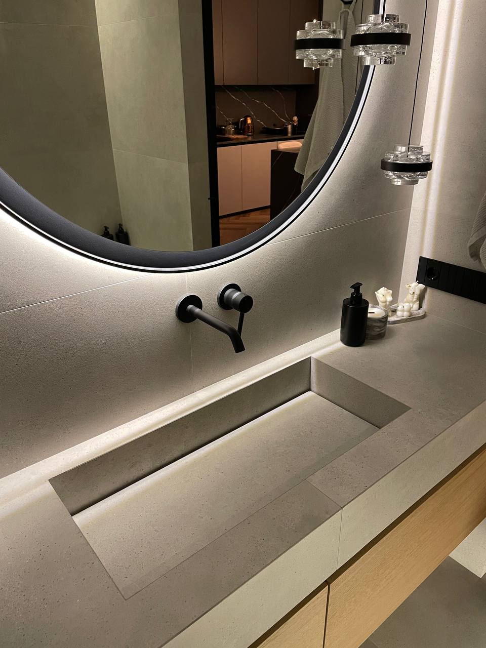 Close-up of integrated concrete sink vanity with backlit black-framed mirror and matte black wall-mount faucet
