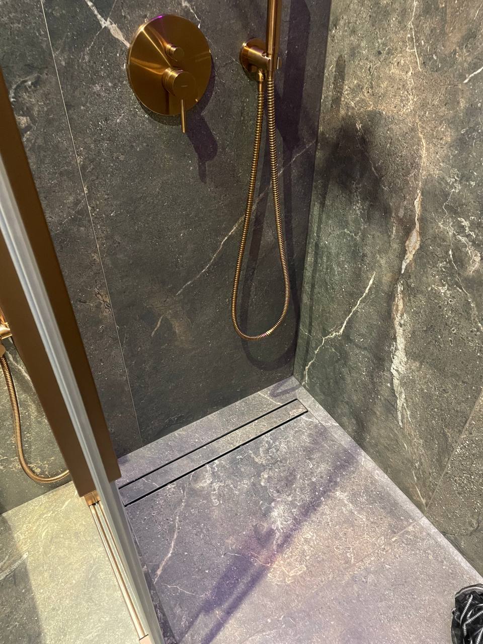 Shower interior with dark marble walls, rose-gold valve and linear drain