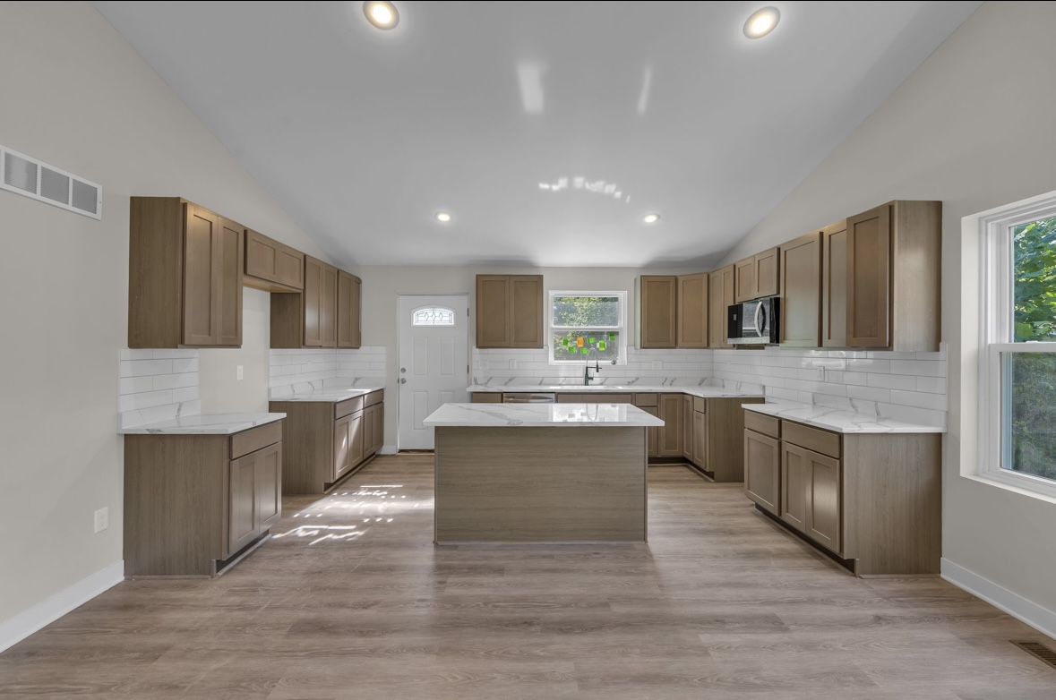 Large open kitchen with wood cabinets, marble countertops and center island