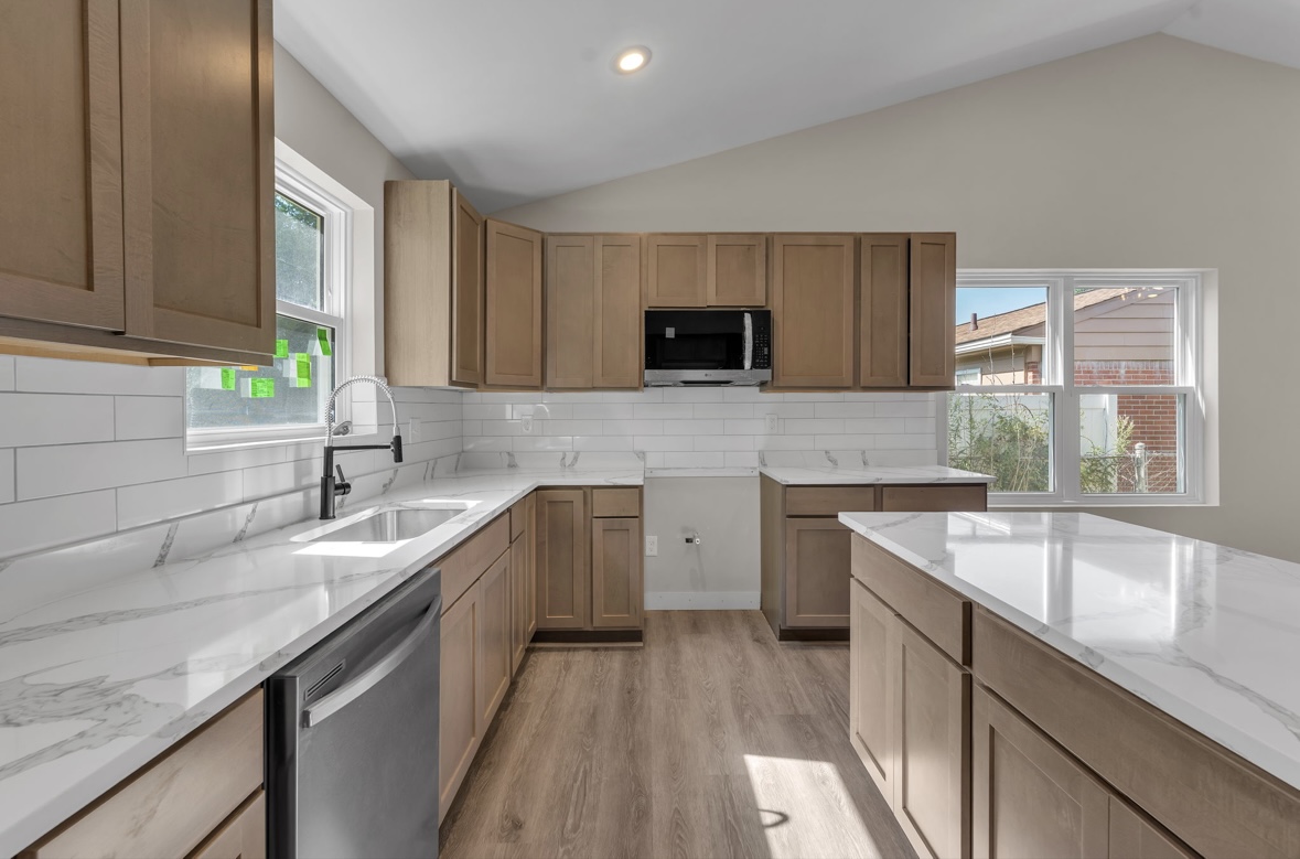 Kitchen with white quartz countertops, black faucet and subway tile backsplash