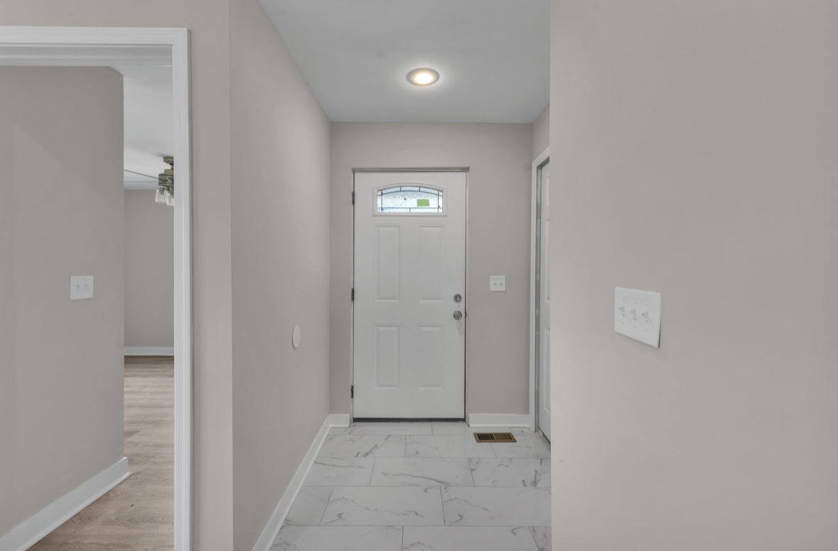 Refinished entryway hallway with marble tile floor and white front door