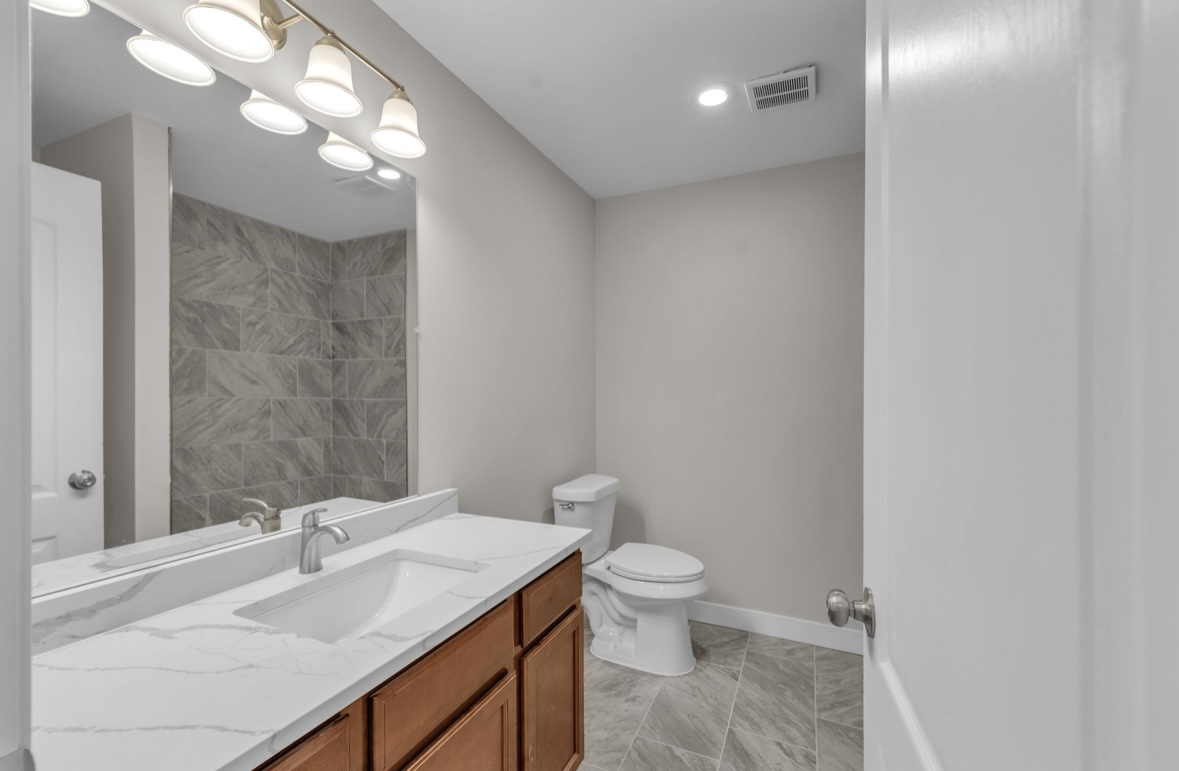 Modern bathroom with marble vanity, wood cabinetry and large mirror