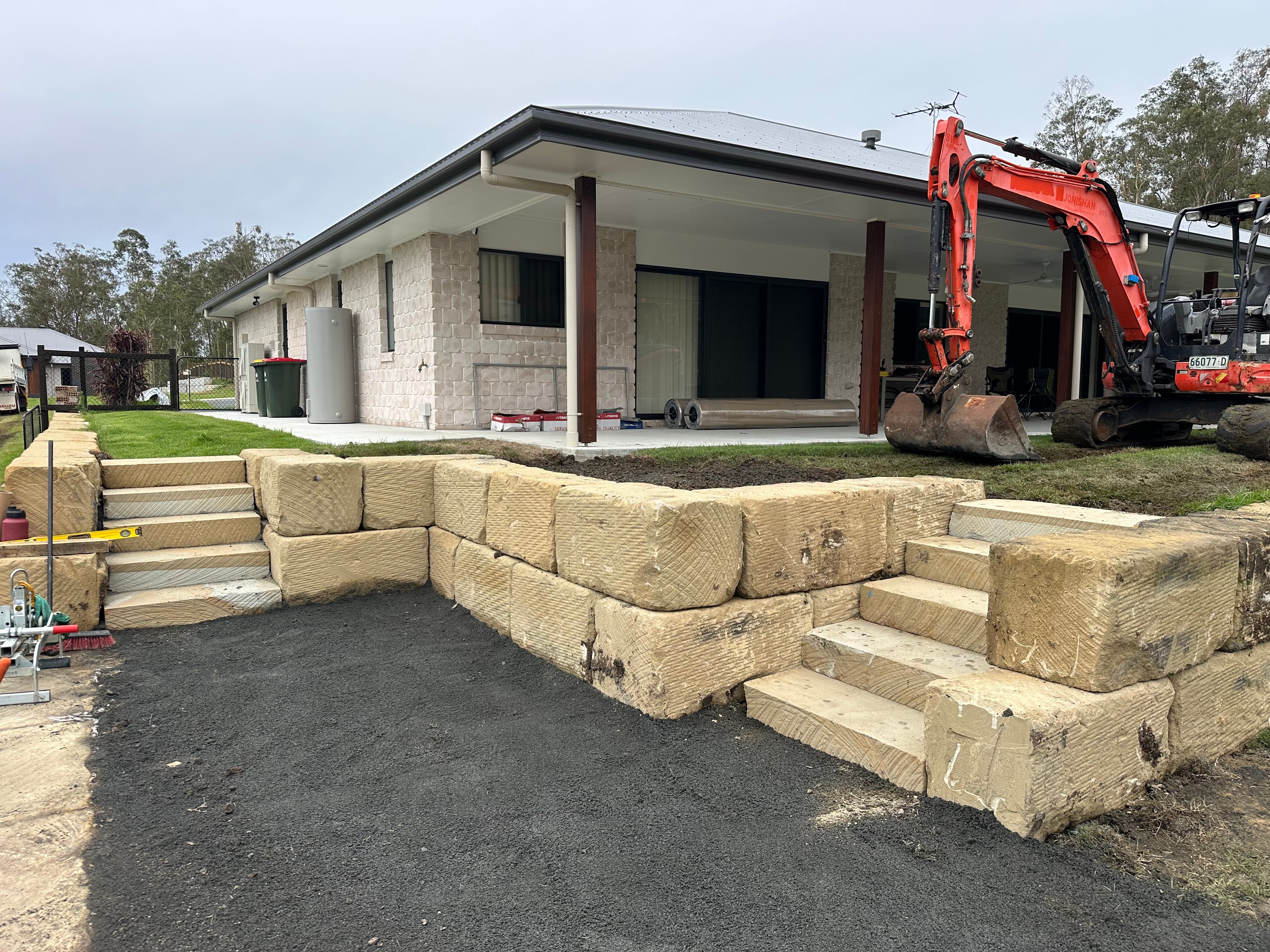 Digtek sandstone retaining wall with integrated steps and excavator on residential project