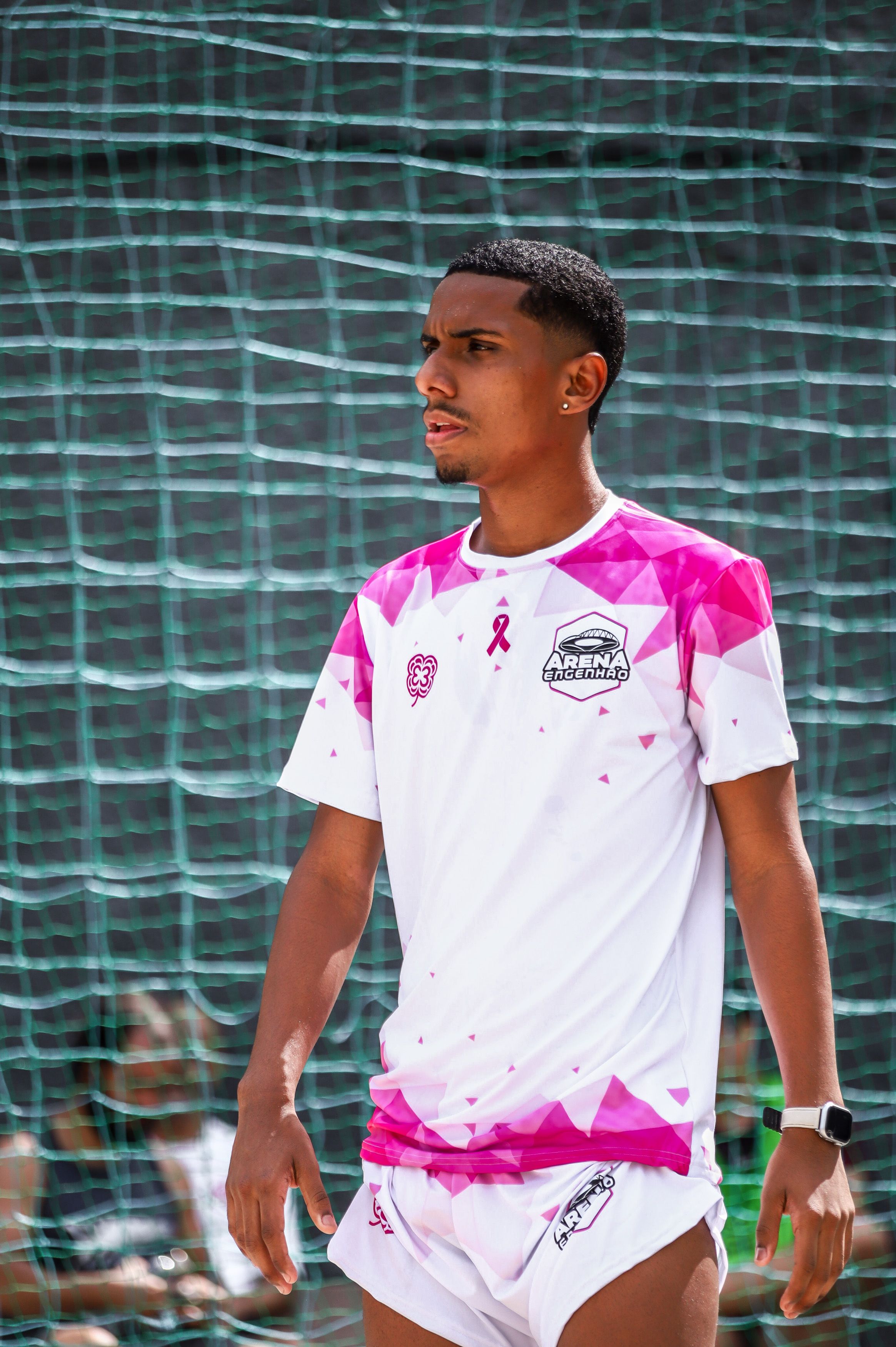 Atleta vestindo uniforme branco e rosa da Arena Engenhão — futevôlei