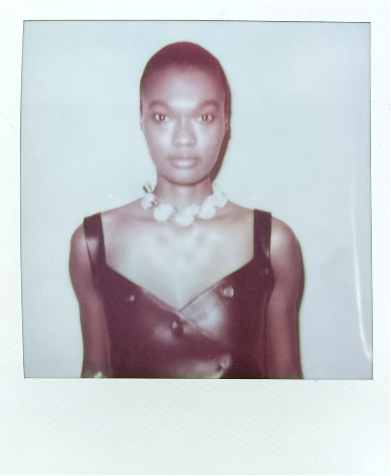 Polaroid portrait woman with shaved head in burgundy wrap with pearl necklace