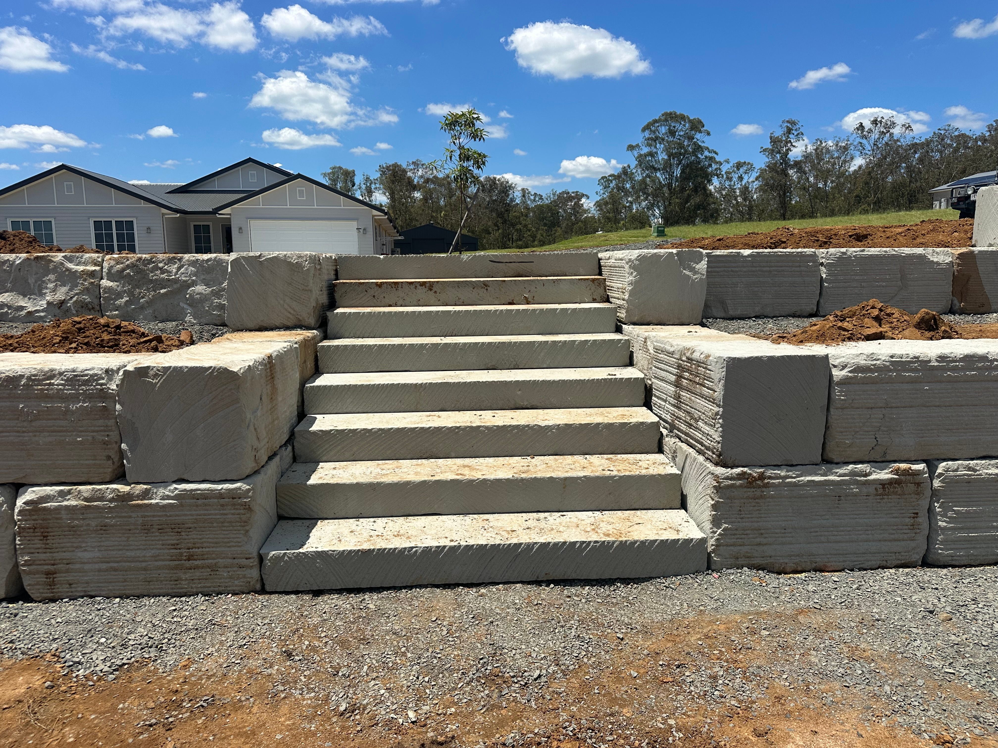 Concrete sleeper retaining wall with integrated steps on residential property
