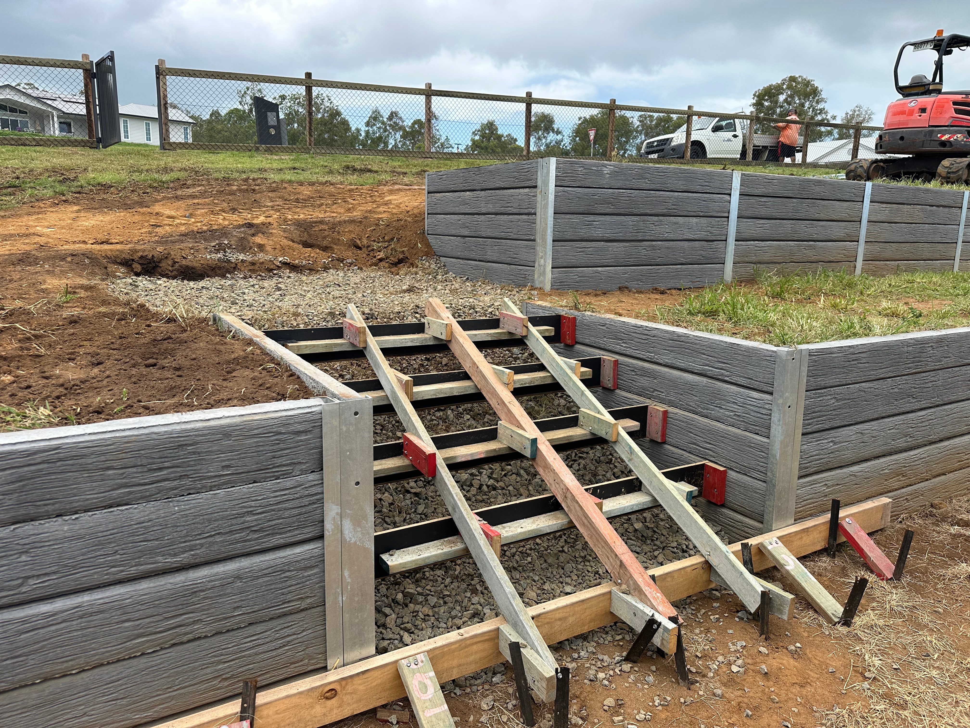 Concrete sleeper retaining wall with steel posts under construction