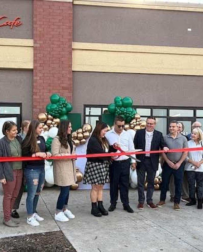Business ribbon cutting with green and gold balloons