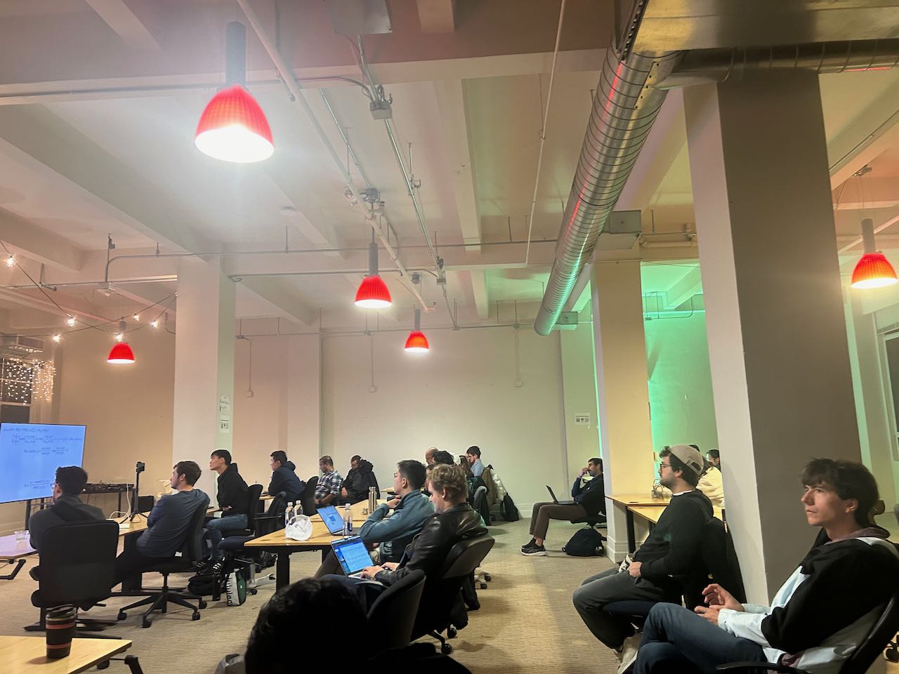 Tech workspace with red pendant lights and laptop users