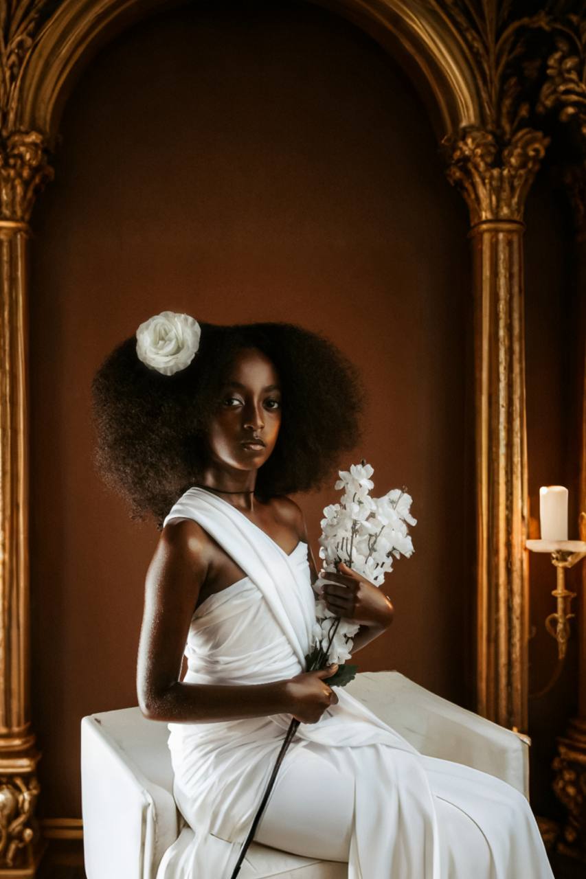Model seated in a white dress holding flowers
