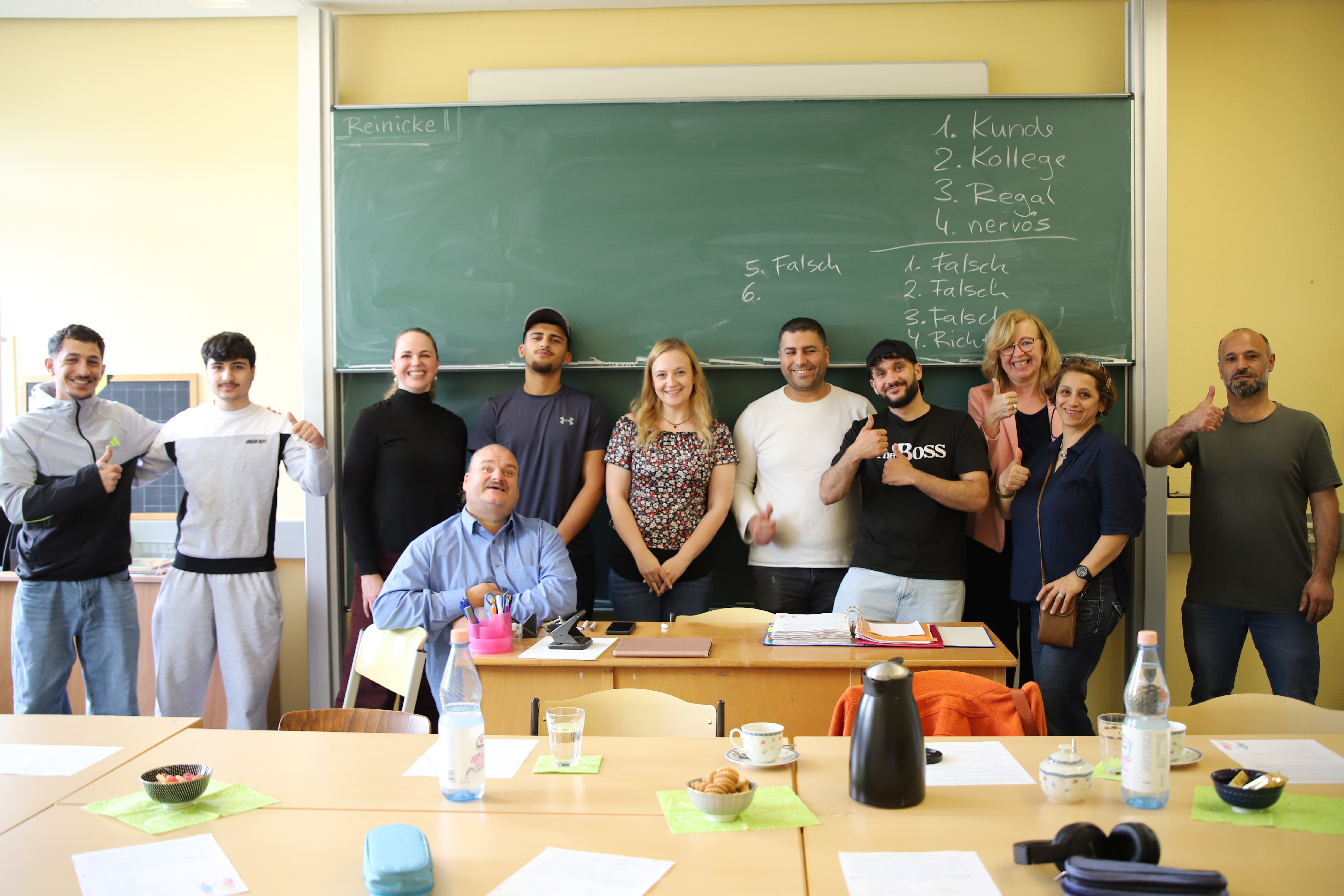 Abschlussgruppen-Porträt vor grüner Tafel mit Vokabeln