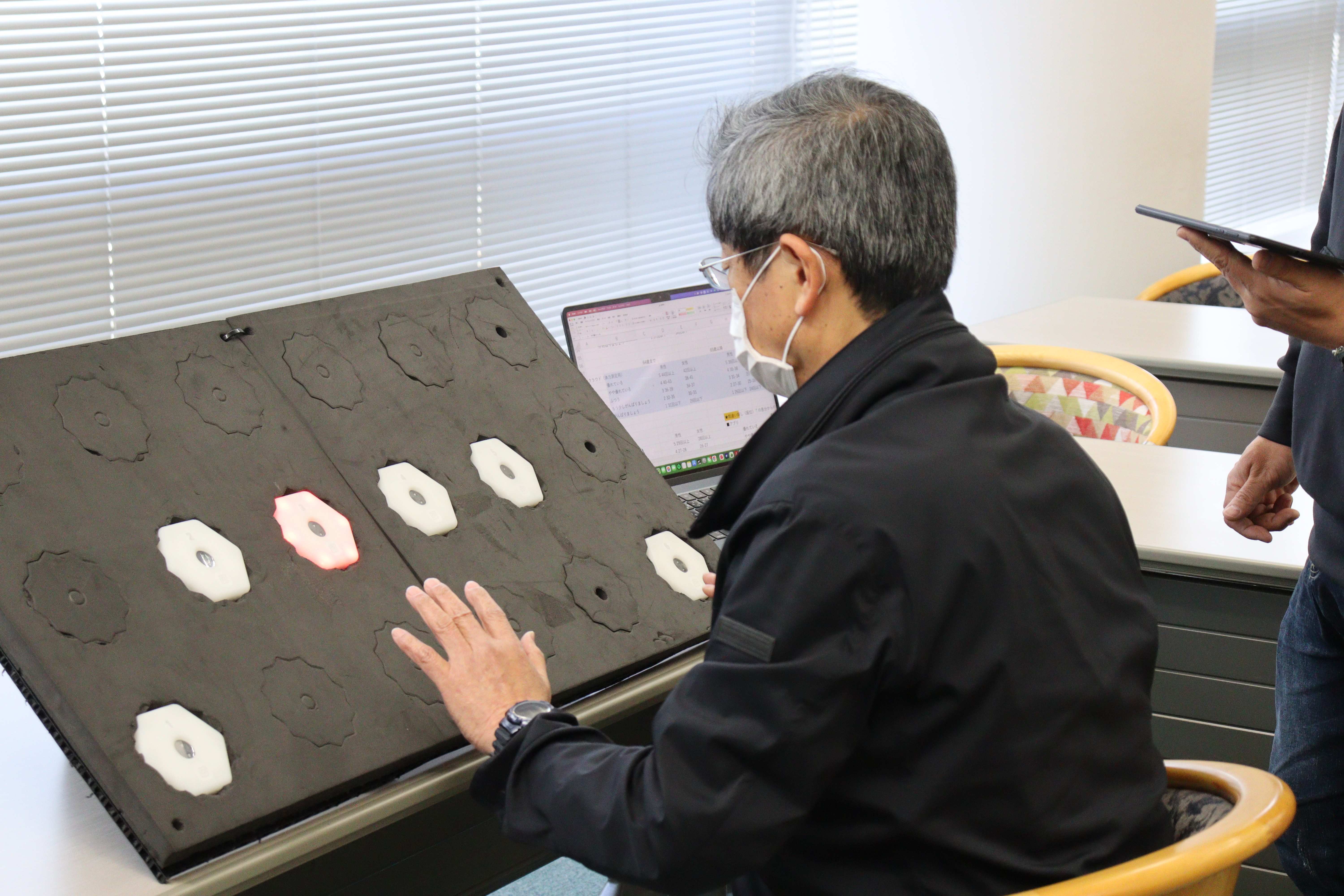 利用者がボードユニットで運動認知測定を行い、光ったユニットに反応している様子