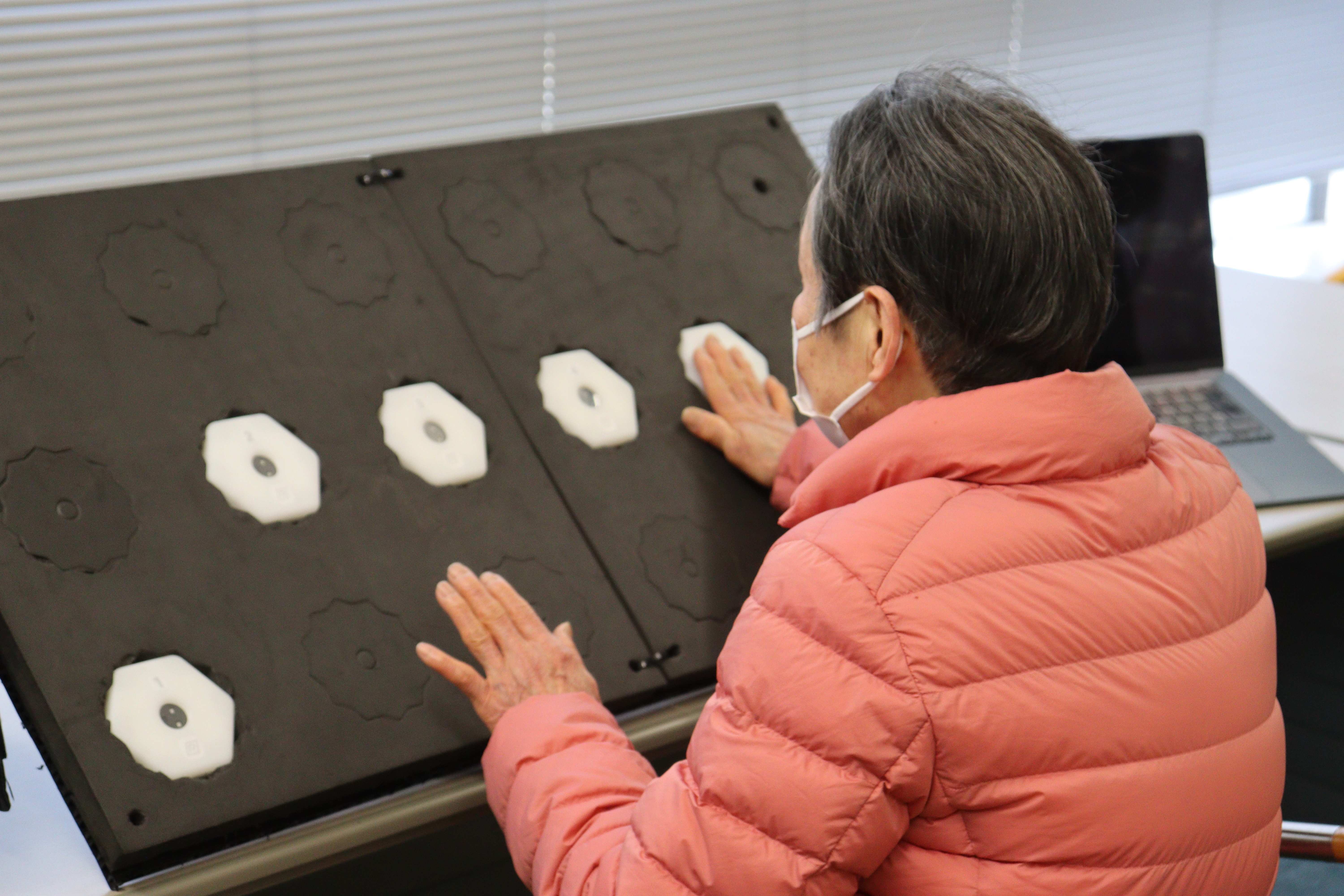 女性利用者が両手を使ってボードユニットの測定を行っている様子