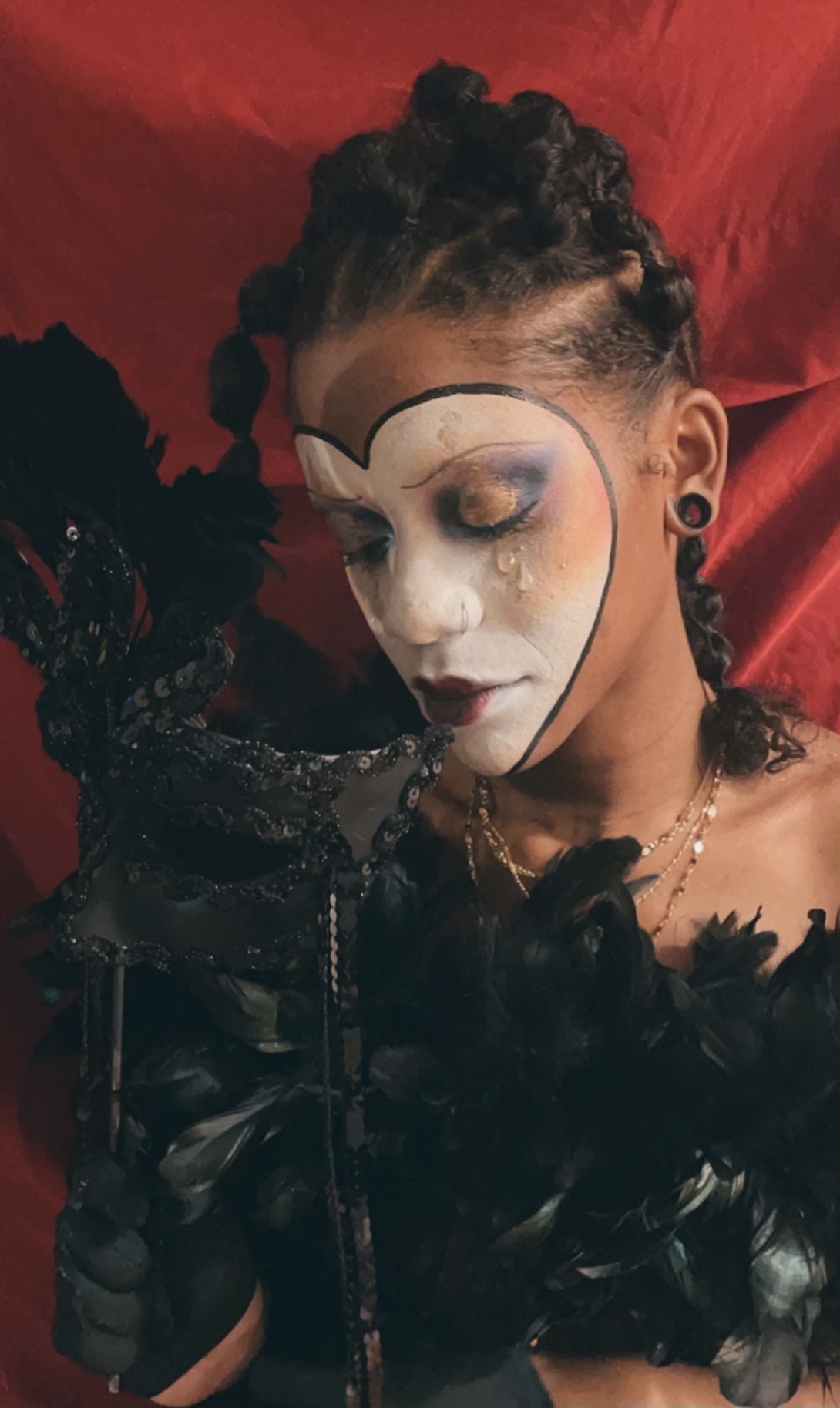 Tajae in theatrical masquerade costume against red backdrop