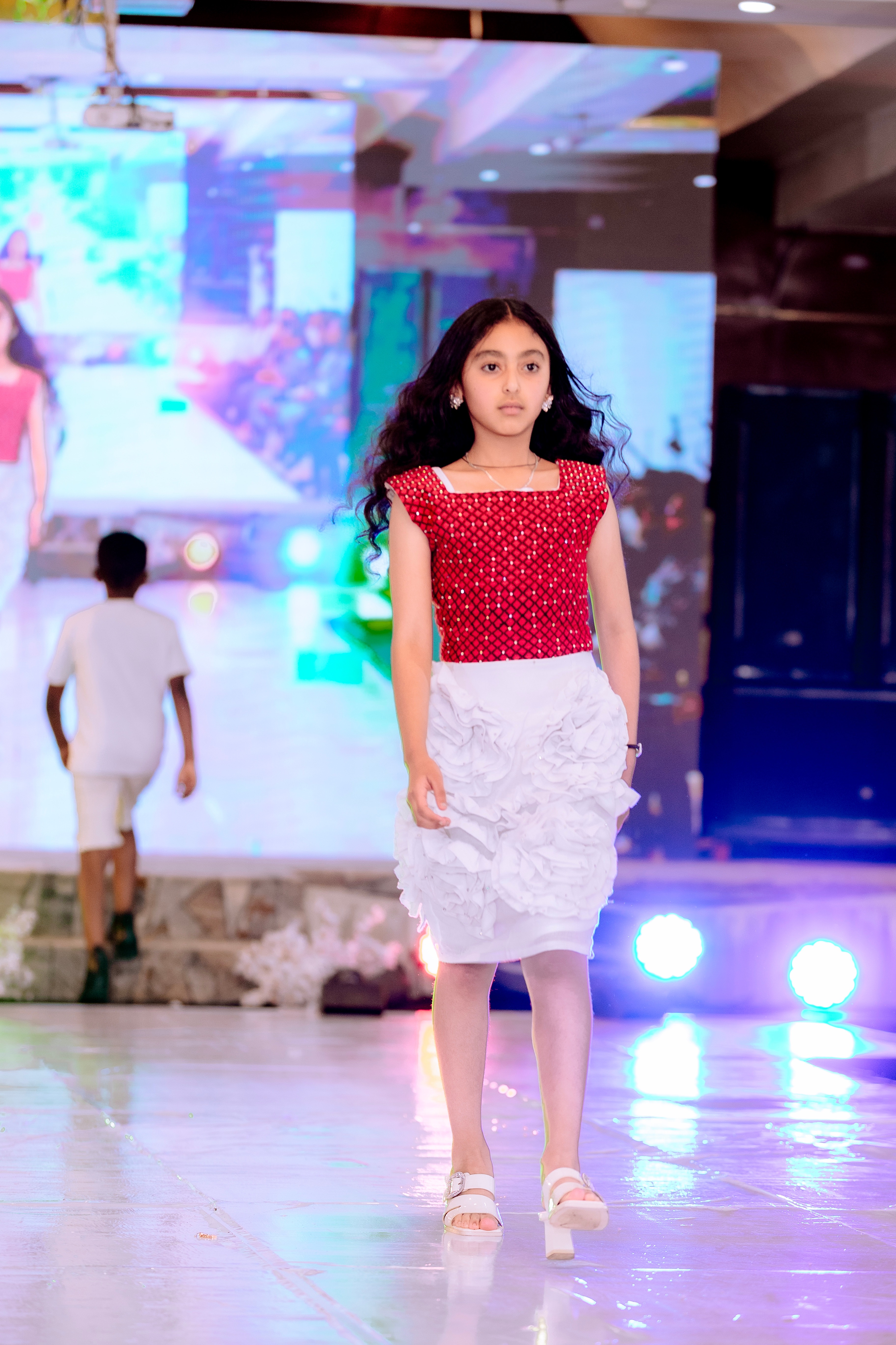 Child model in a white dress carrying a parasol