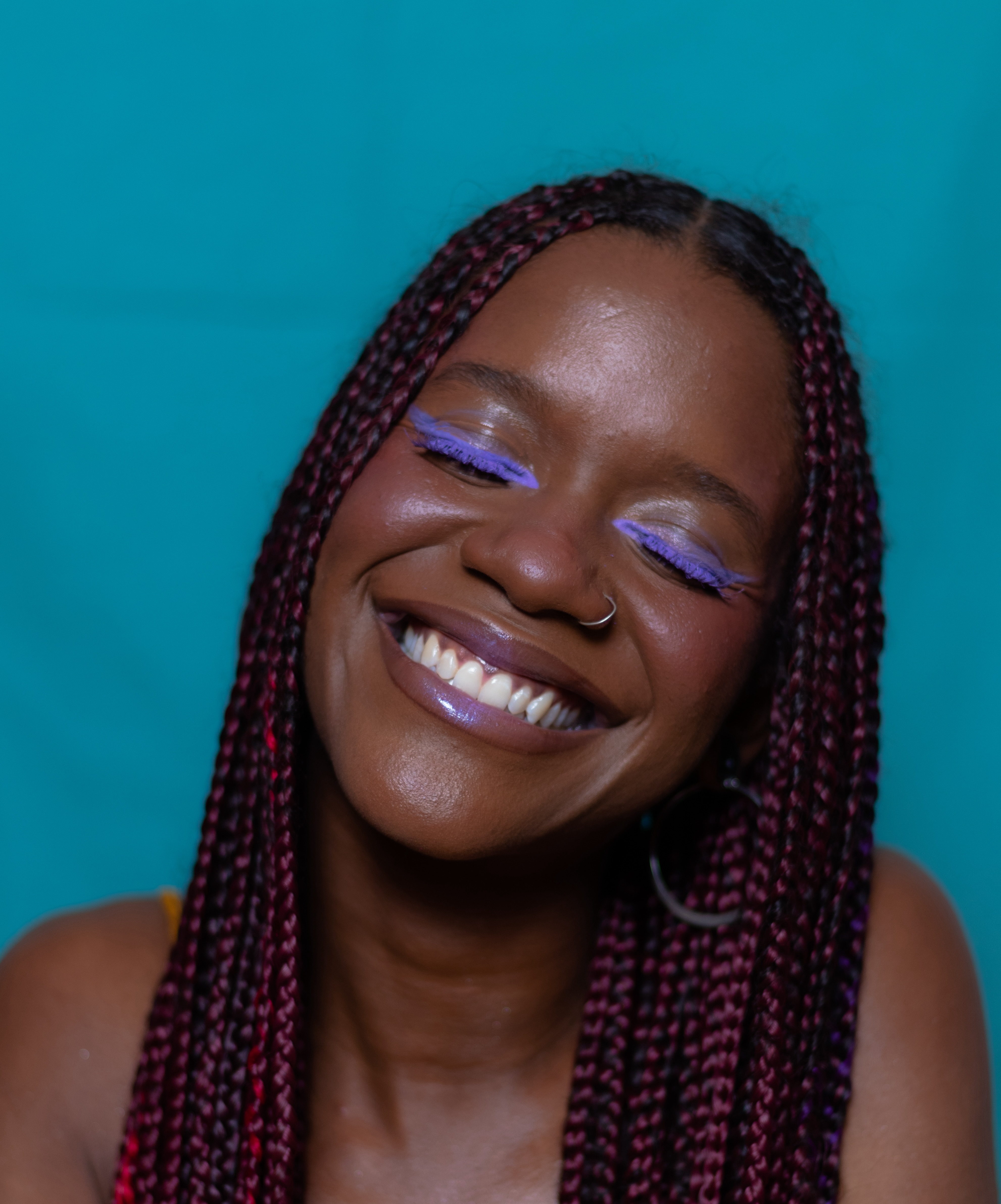 Smiling portrait with teal background and red braids