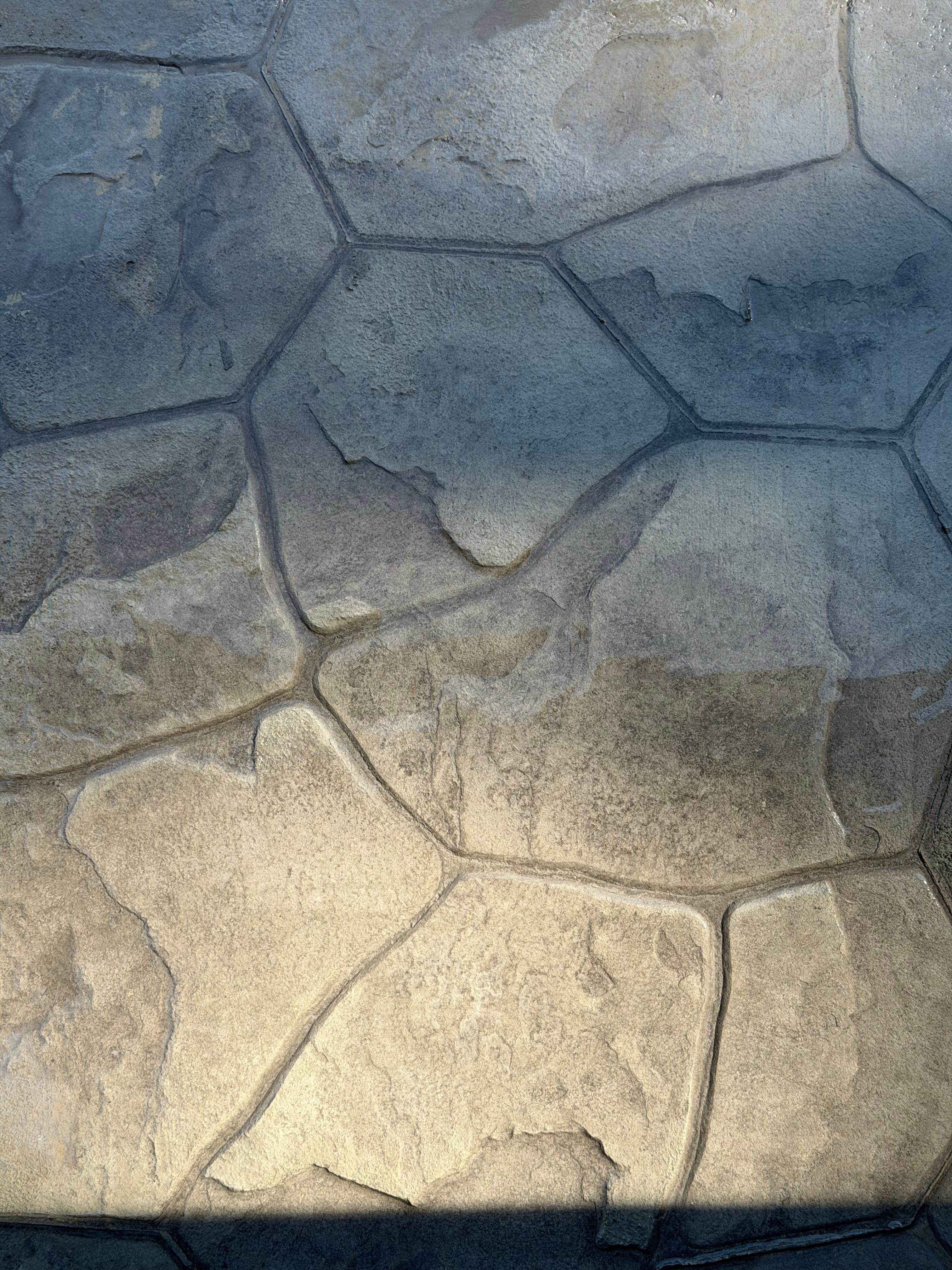 Antiqued flagstone-pattern stamped concrete with a blue-gray to warm tan finish