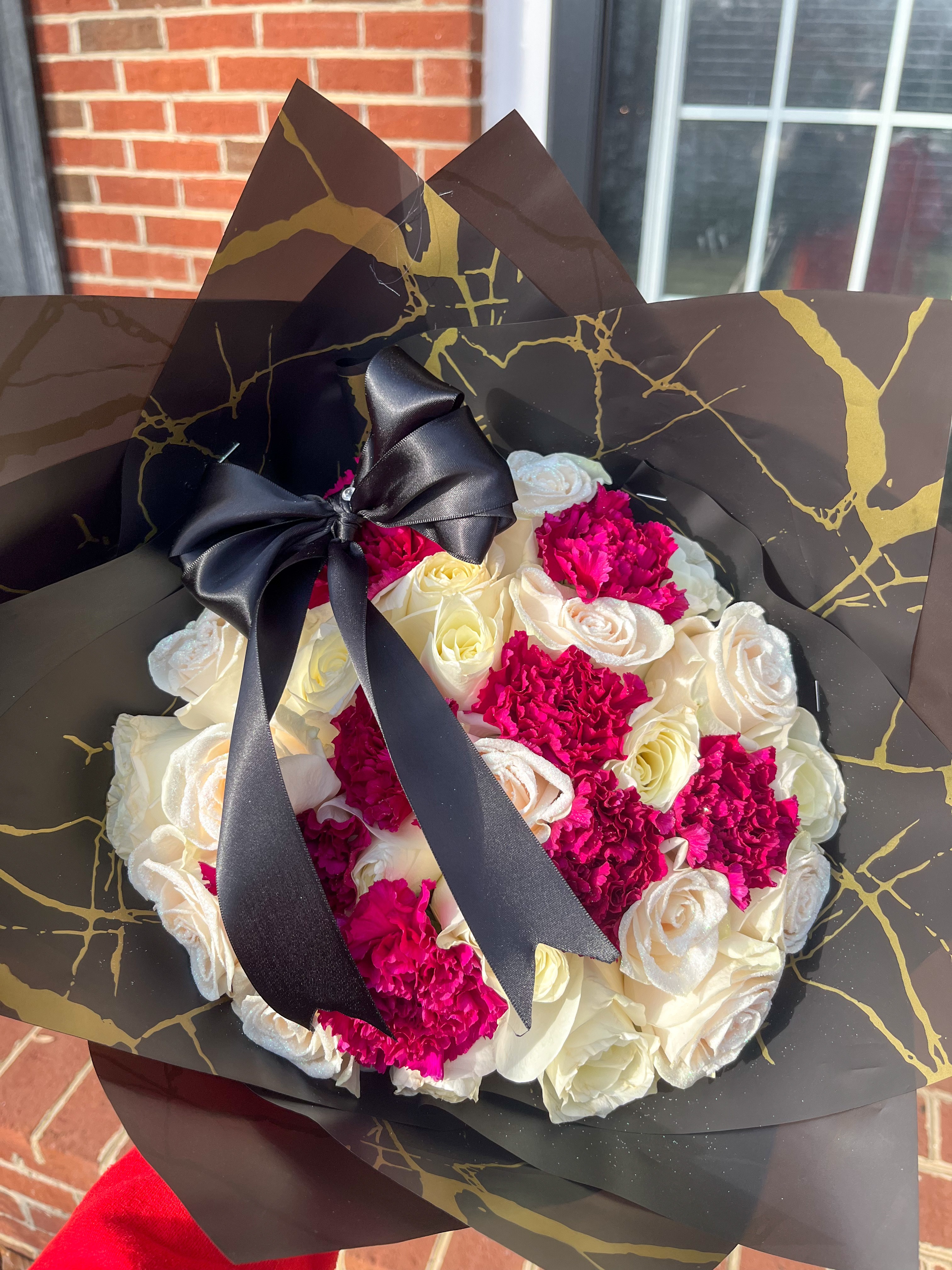 White roses with hot pink carnations in black wrapping