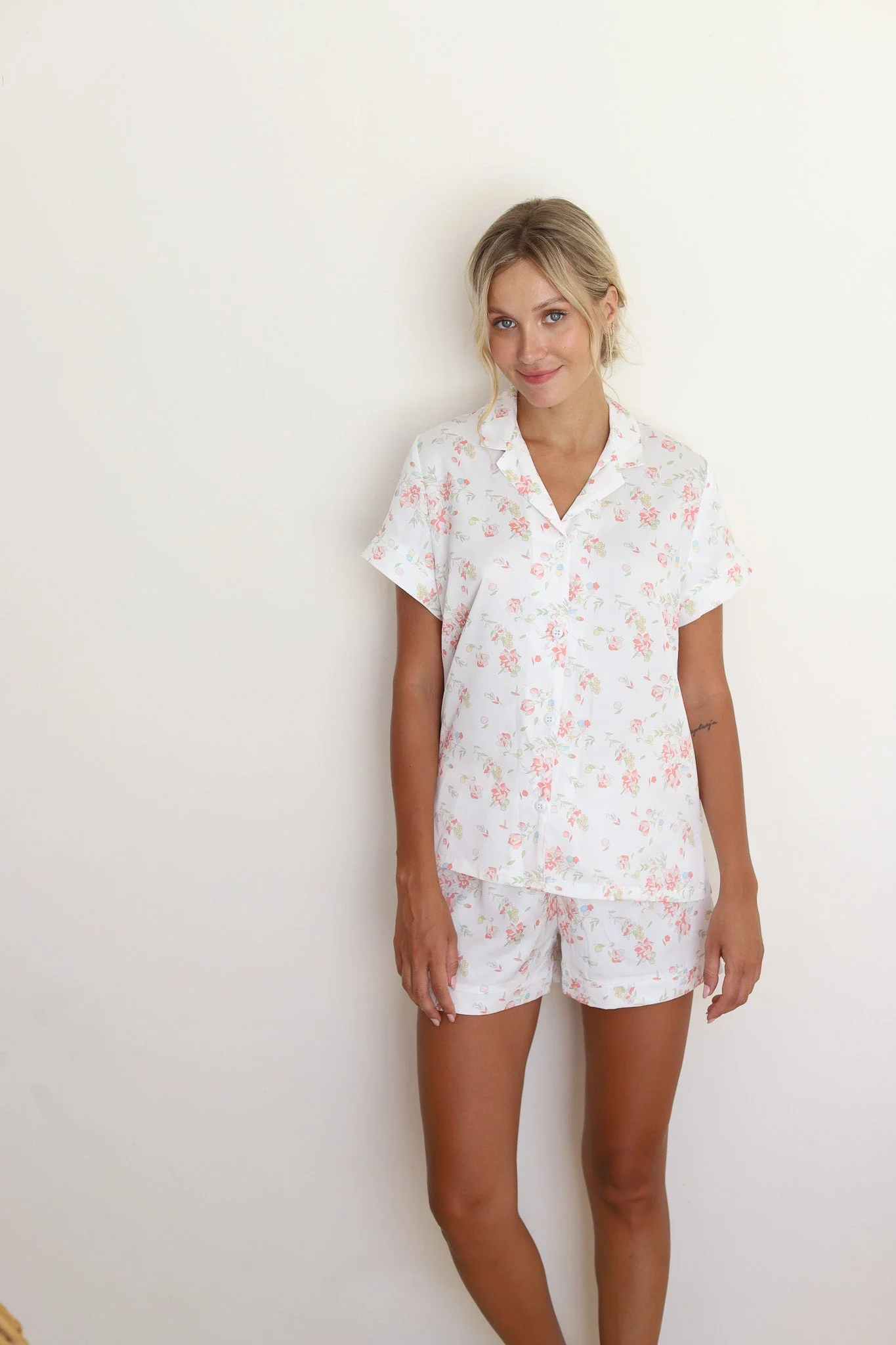 A satin matching button-front short-sleeve top and shorts in a delicate white-ground floral print.