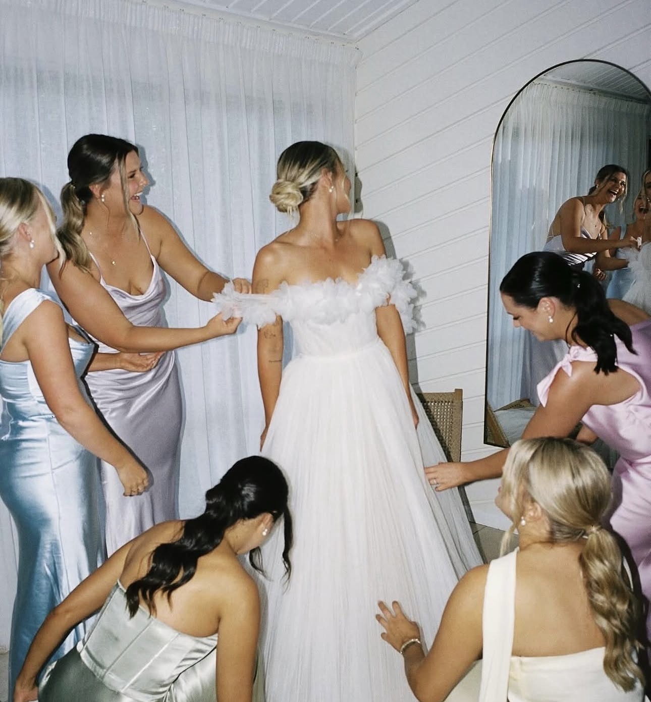 Bridesmaids helping the bride into her gown