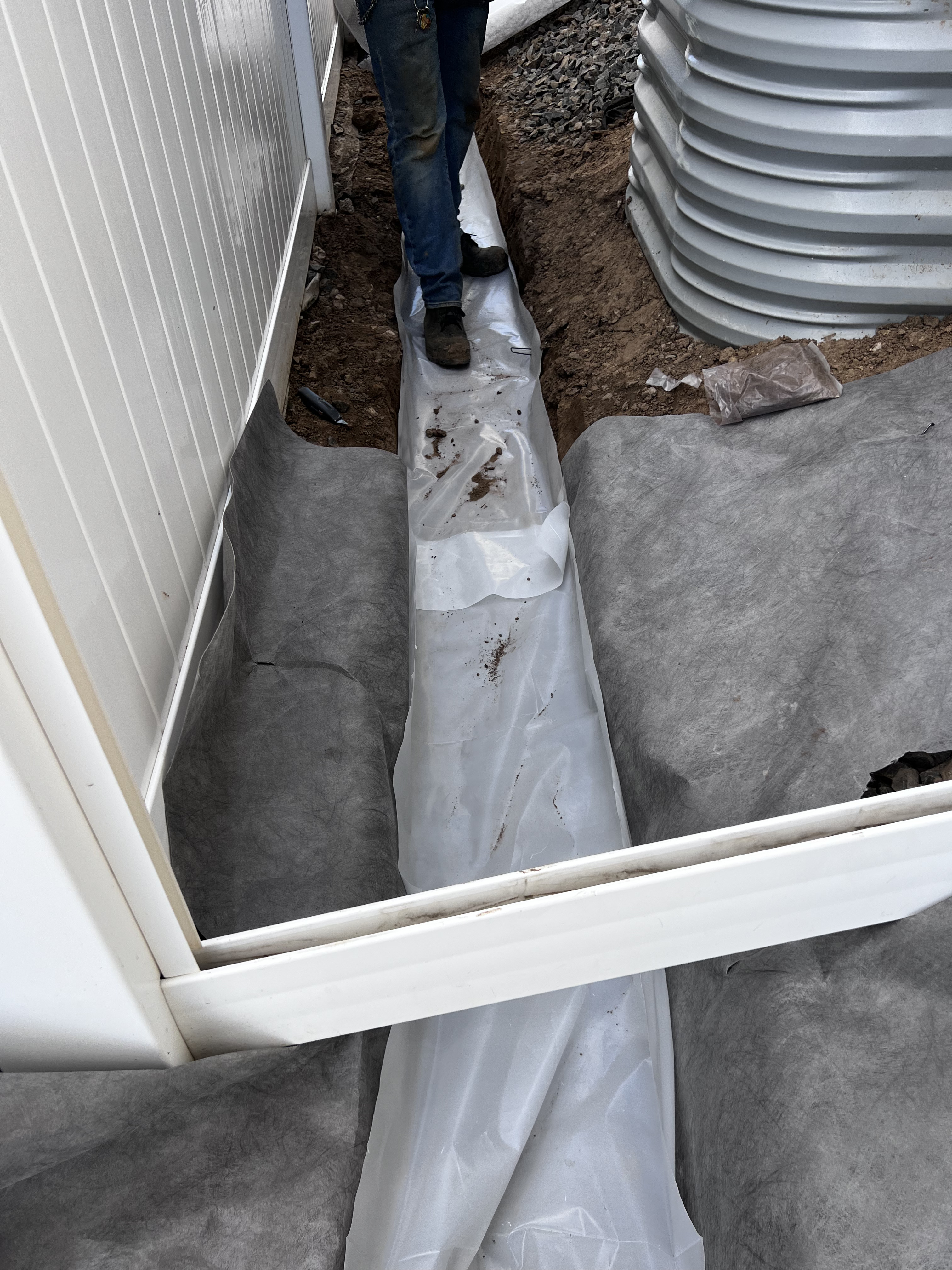 French drain waterproofing along foundation with window well