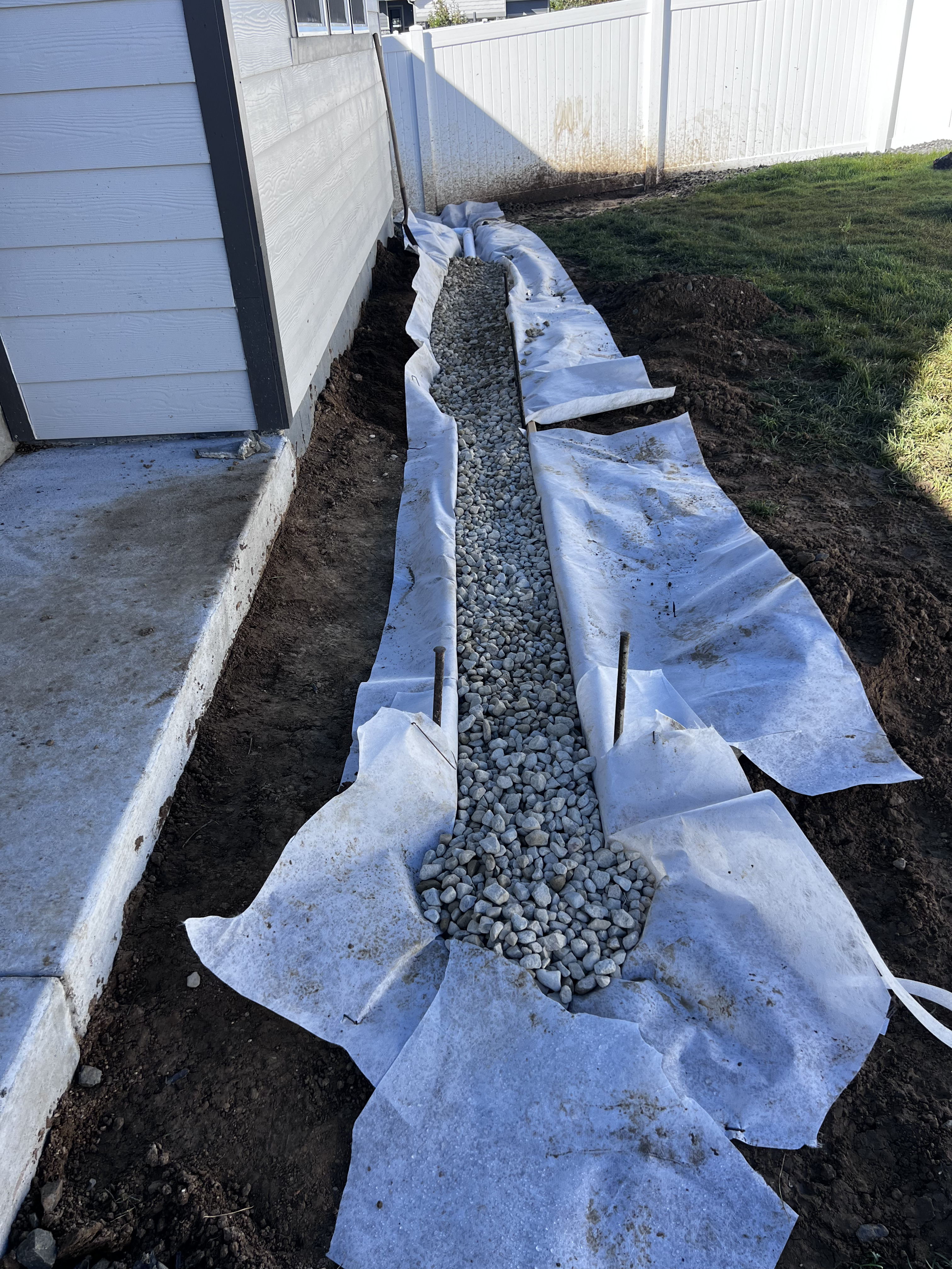 French drain installation with filter fabric and river rock gravel