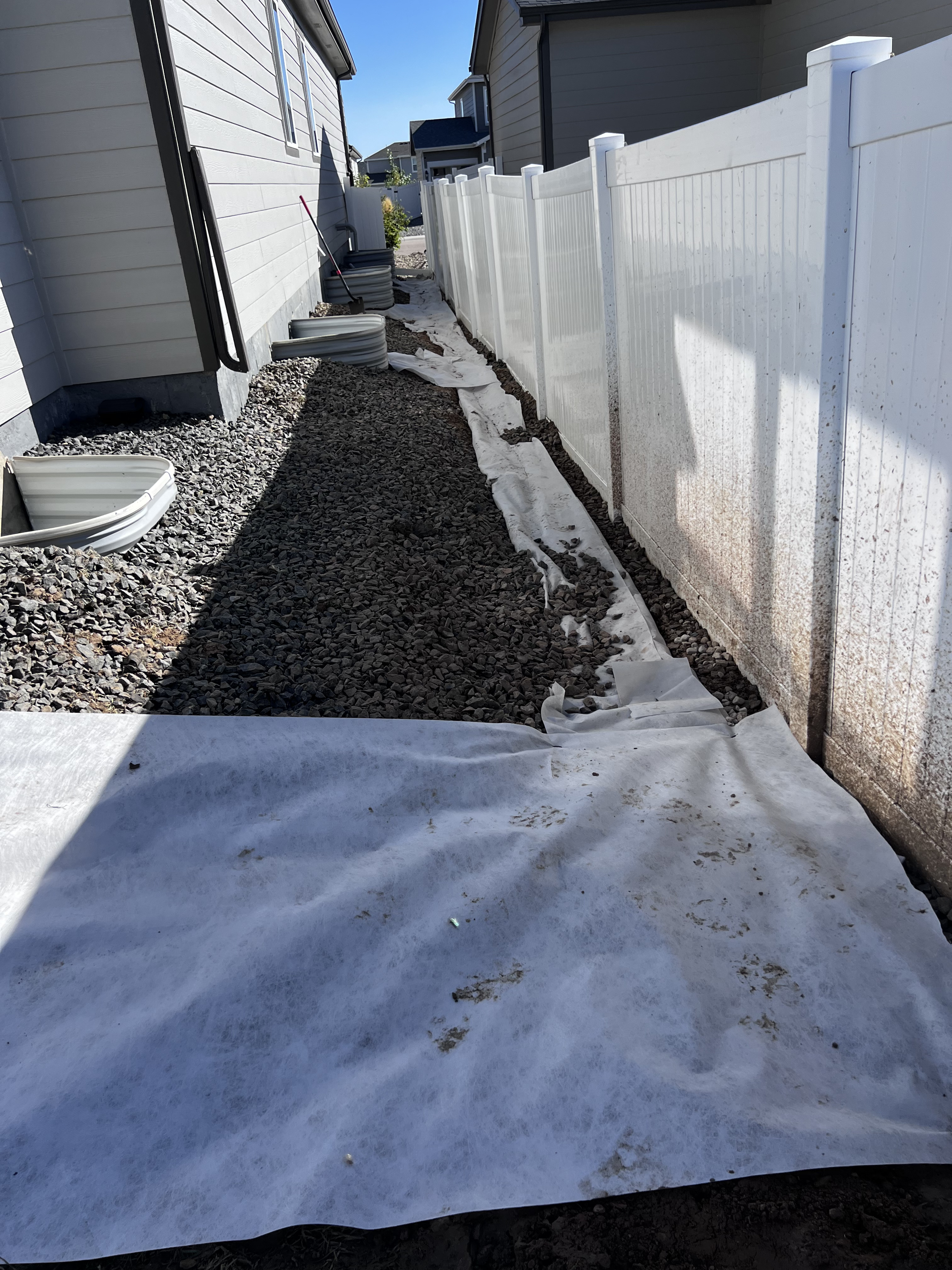 French drain installation in progress with gravel and fabric