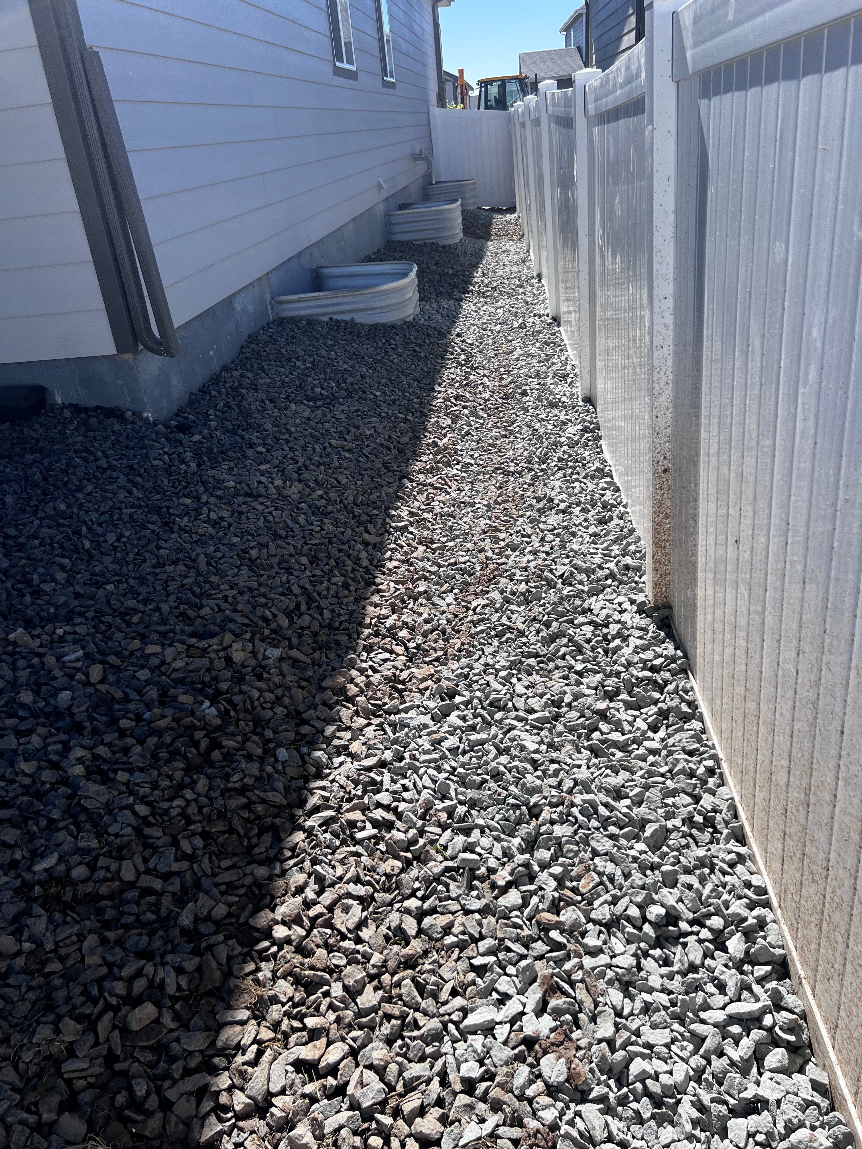 Completed gravel path along side of house with window wells