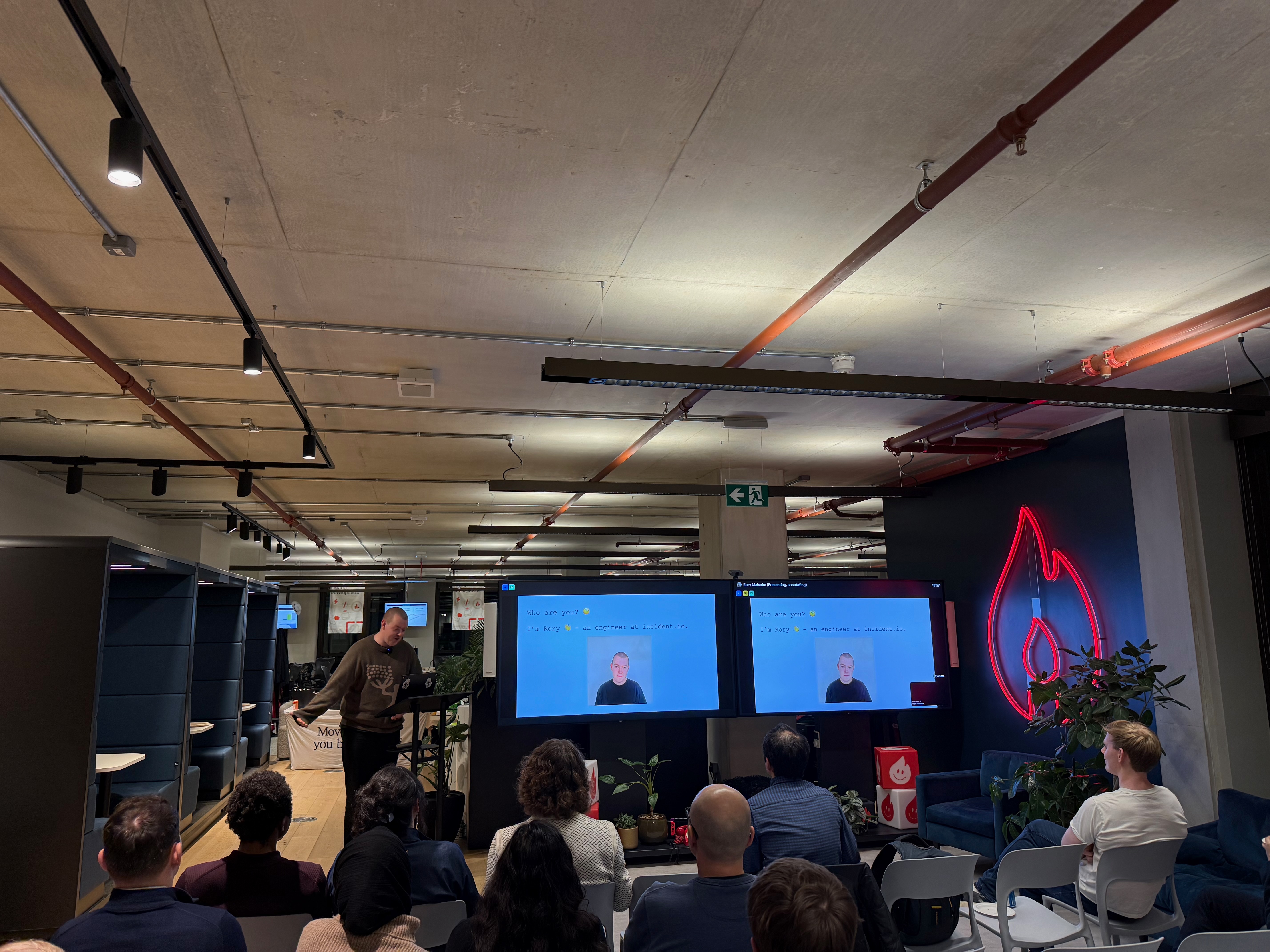 Rory Malcolm presenting at a community meetup with neon flame backdrop