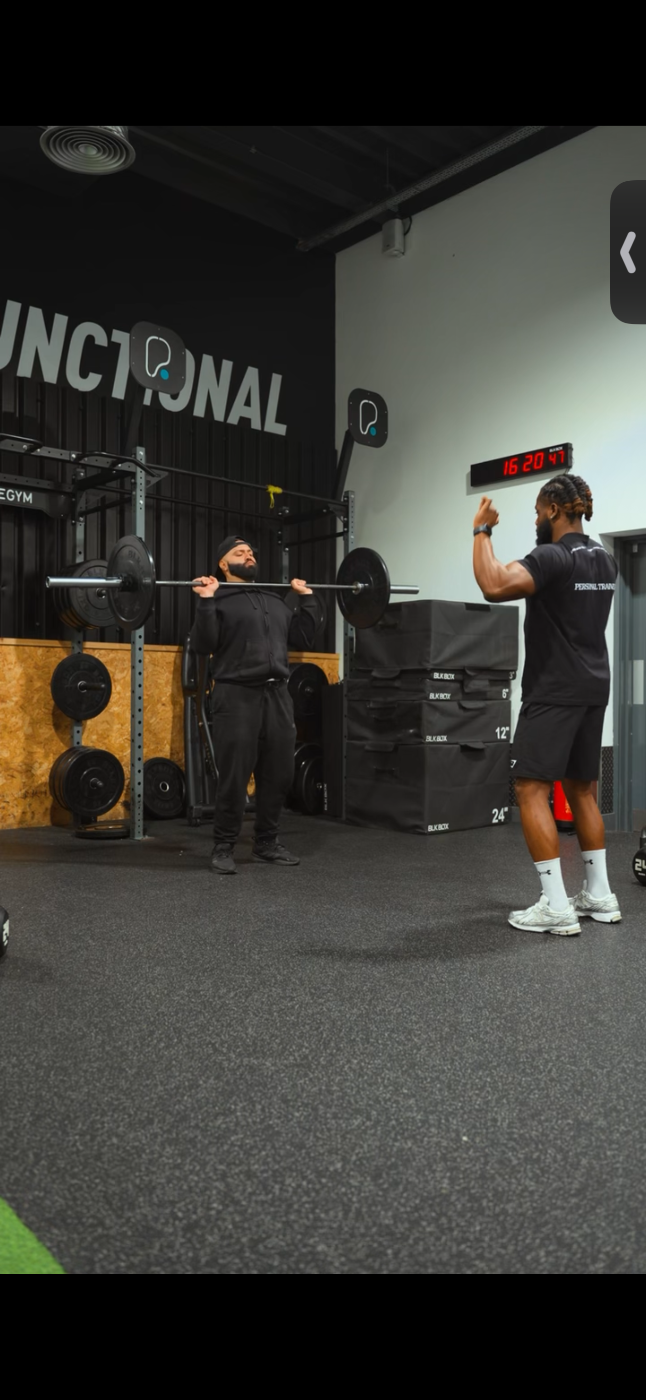 Fadel coaching a client during a barbell exercise at the gym