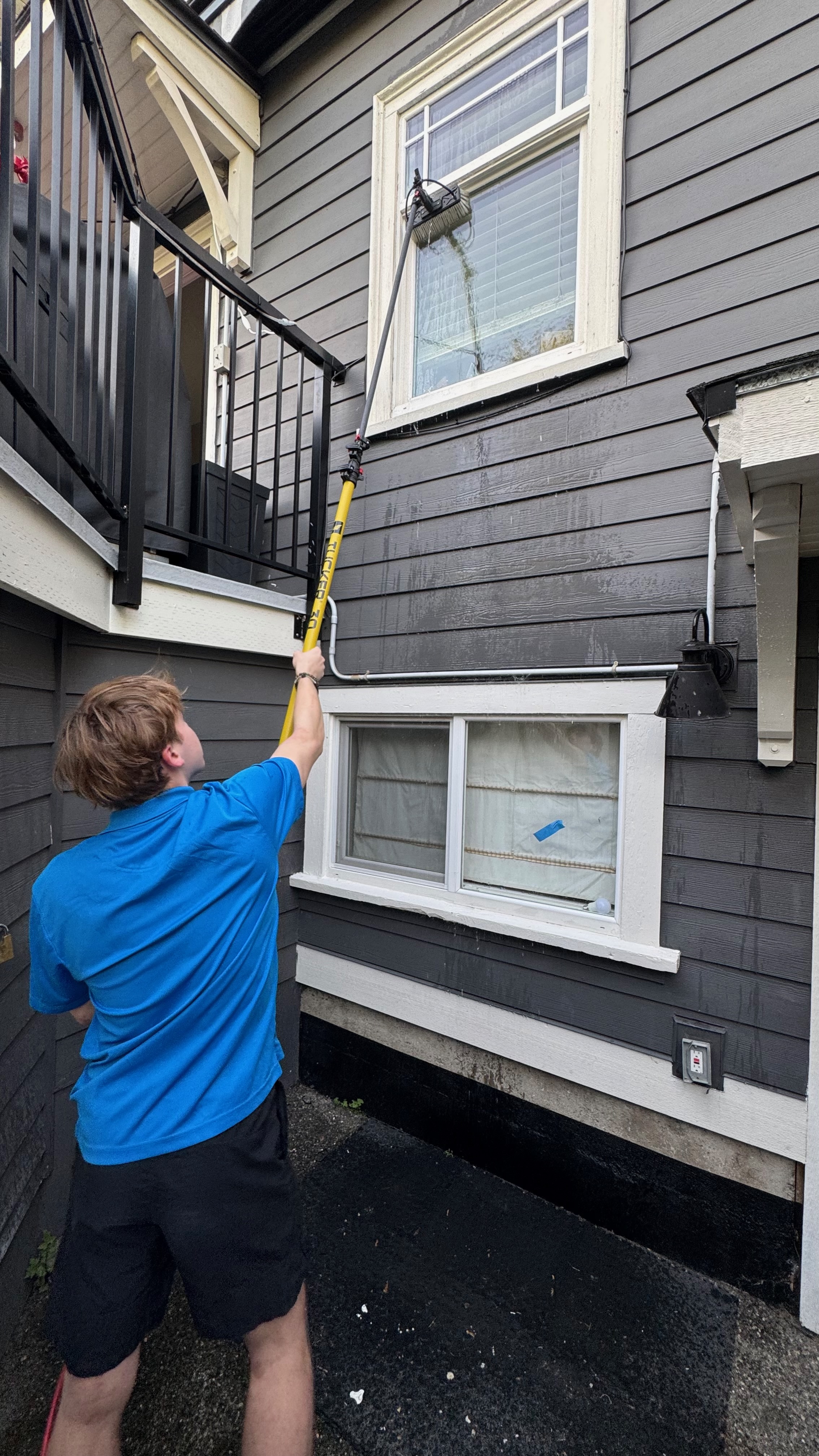 Chris reaching up with the water-fed pole to clean second-storey windows