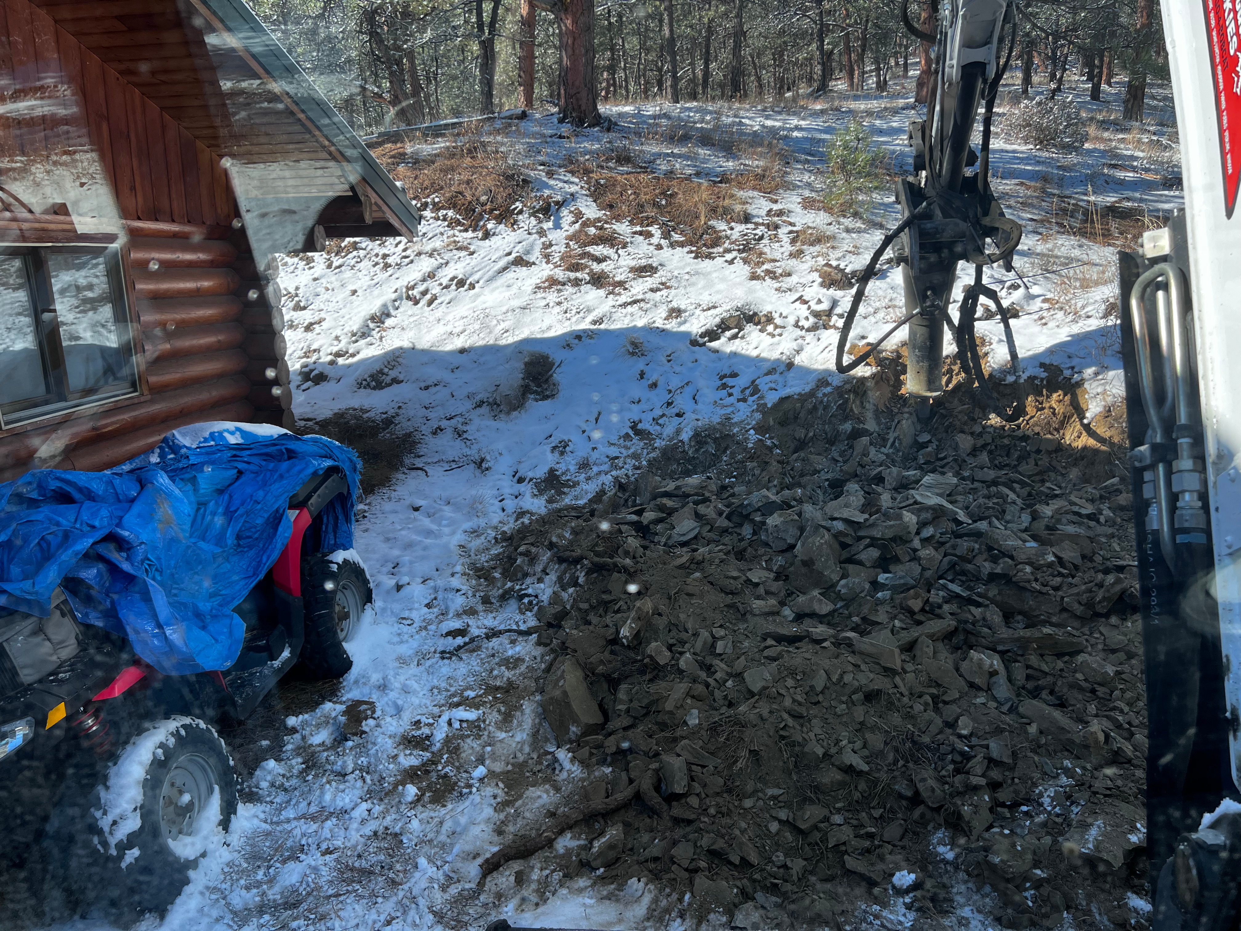 Mini excavator working next to log cabin in snowy conditions