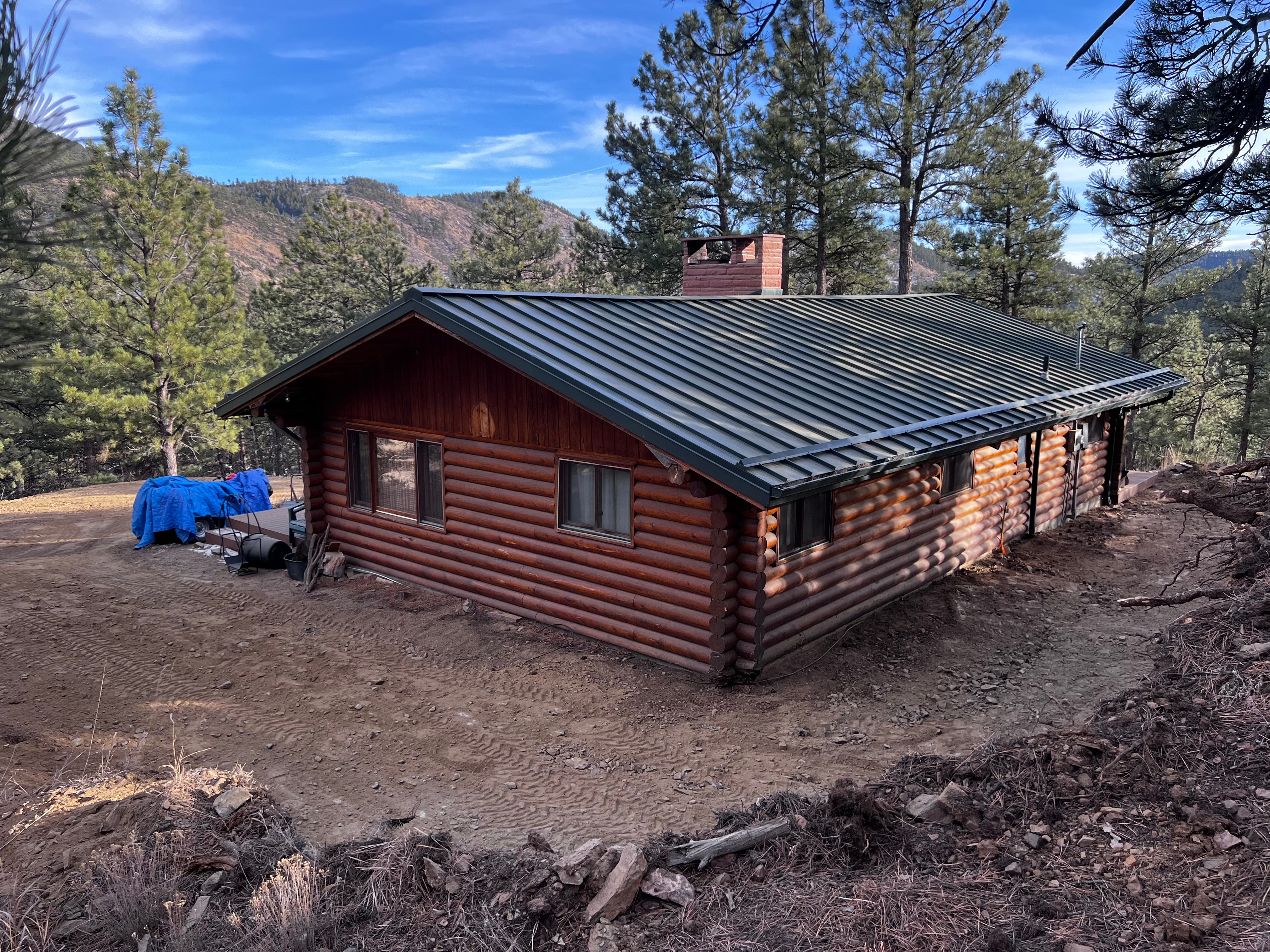Log cabin with graded dirt driveway in Colorado mountains