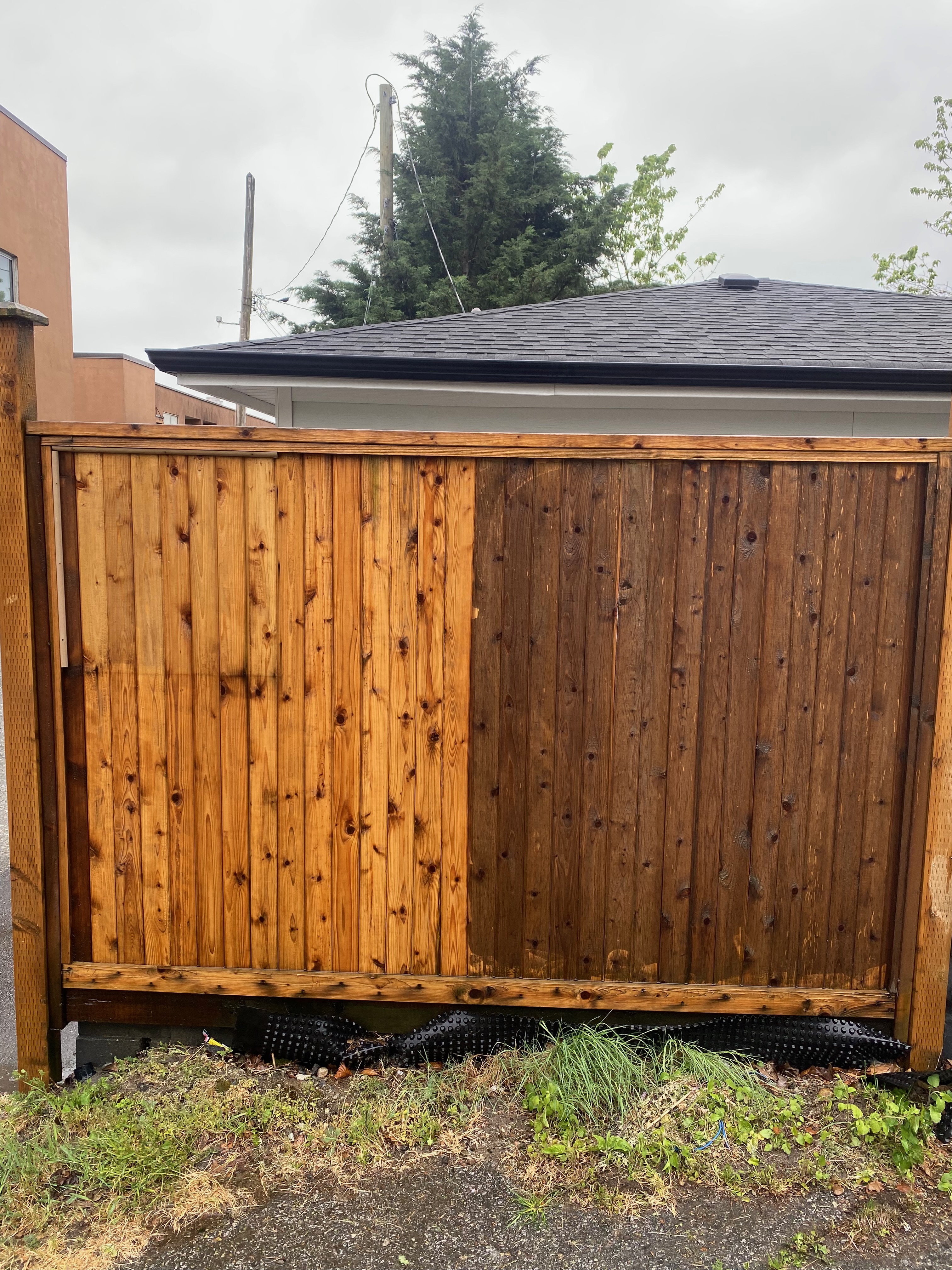 Wooden fence before and after cleaning — left side bright and clean, right side dark and dirty
