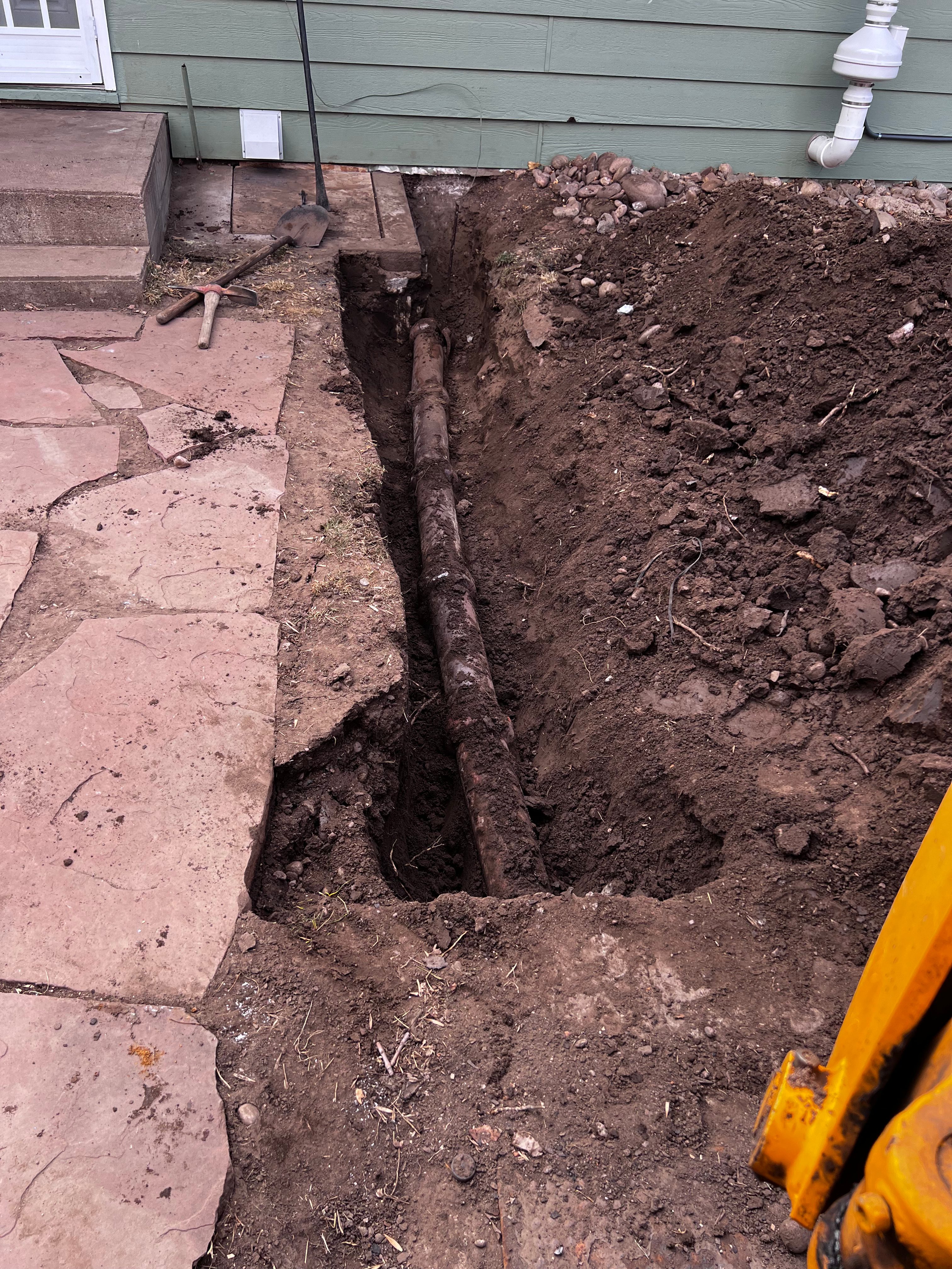 Old cast iron sewer line exposed in trench for repair