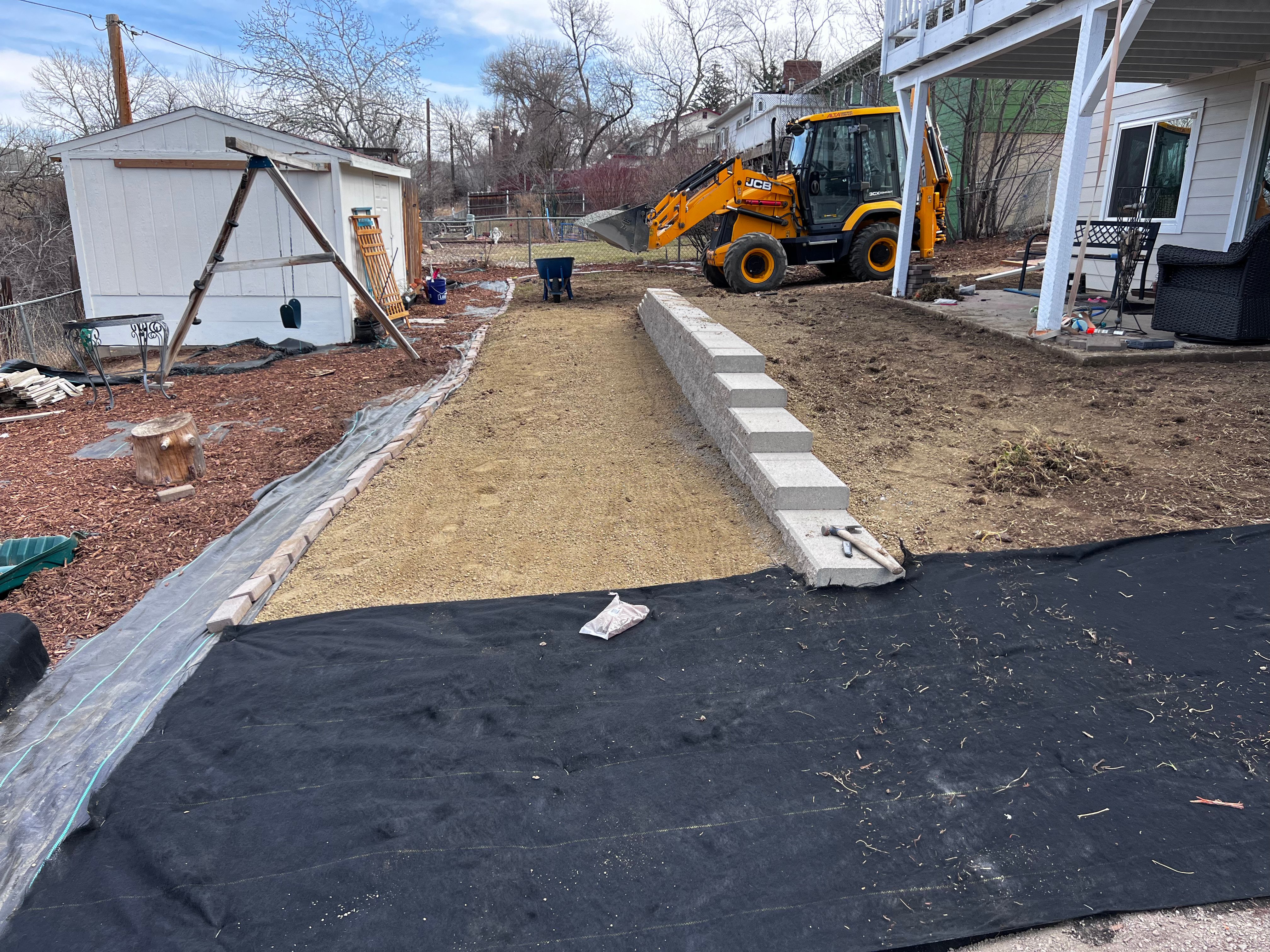 Site grading with JCB backhoe and concrete retaining wall blocks