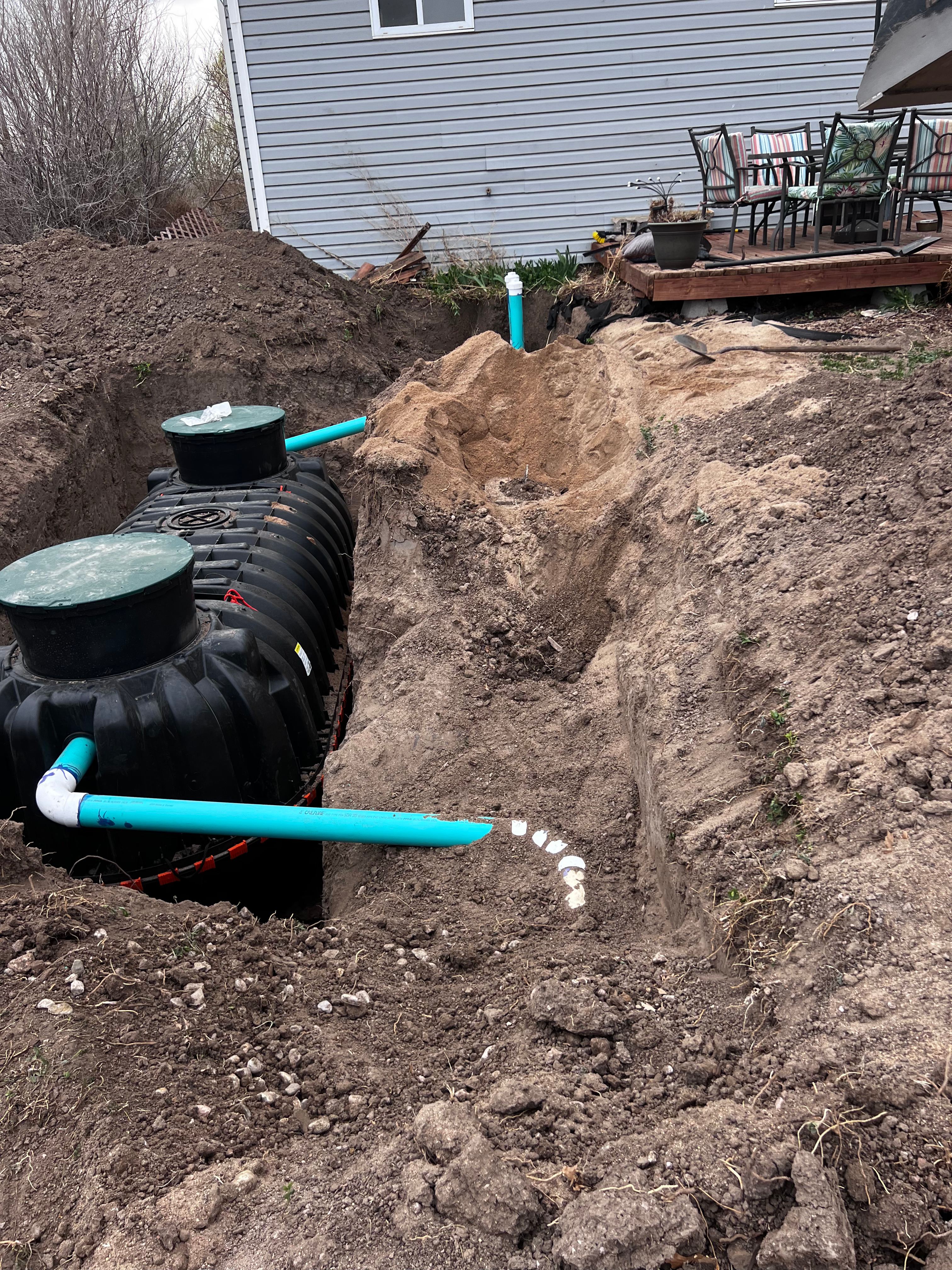 Black septic tank installation in excavated pit with PVC pipes