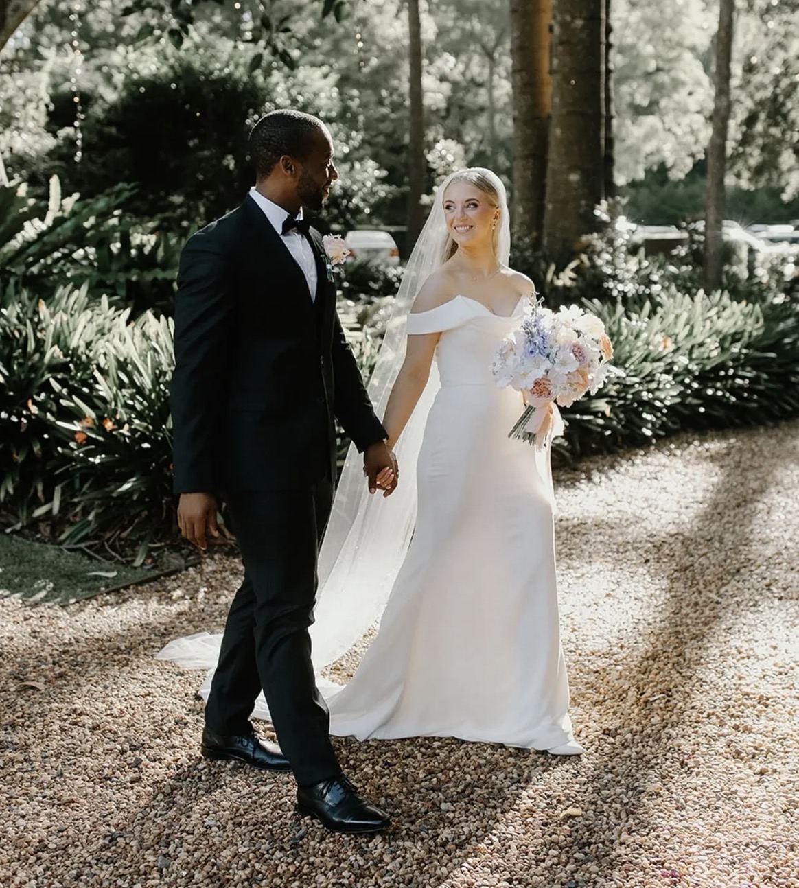 Bride and groom holding hands among lush gardens