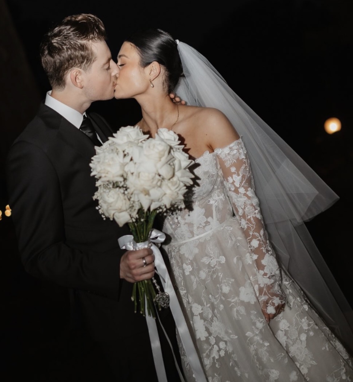 Bride and groom sharing a kiss, bride in a lace gown and veil