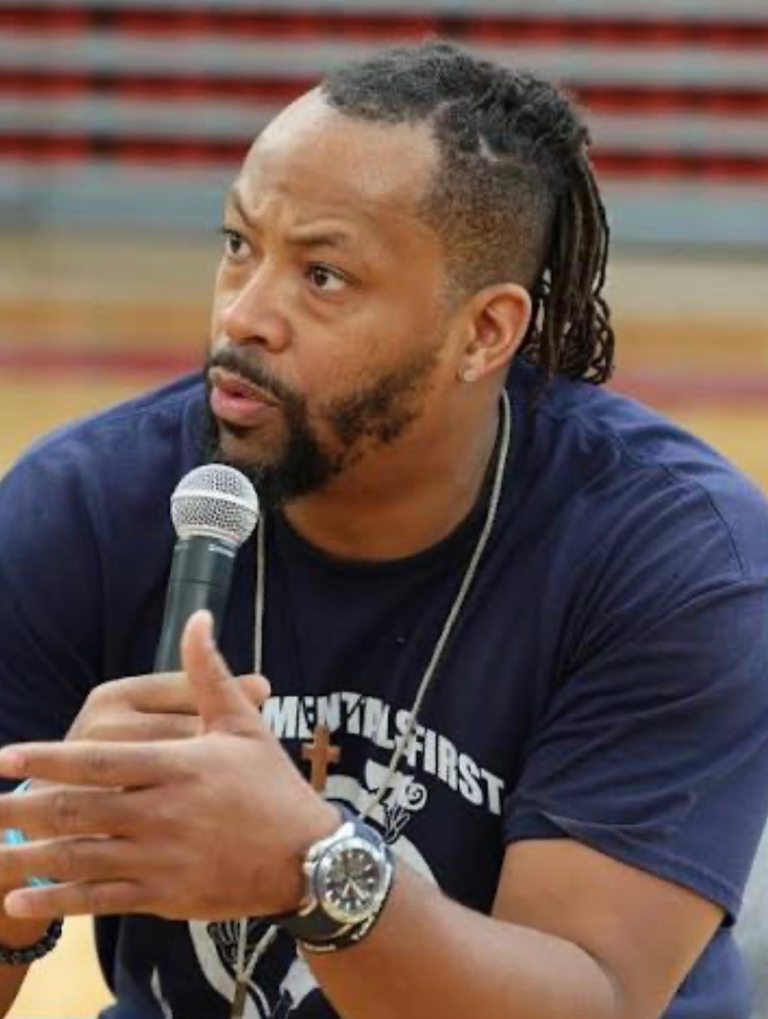 Wesley Fluellen speaking with microphone in gymnasium