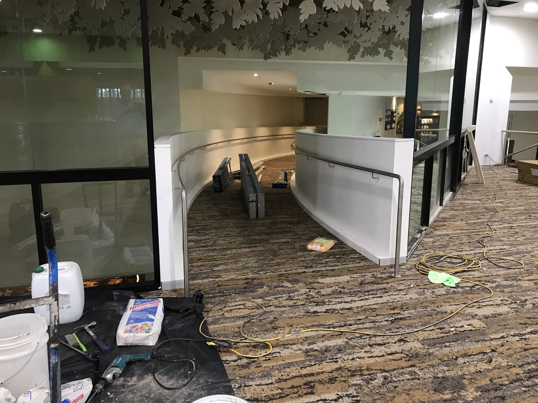 Curved metal handrail installation beside a commercial ramp