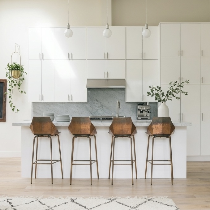 White kitchen with marble backsplash and copper bar stools