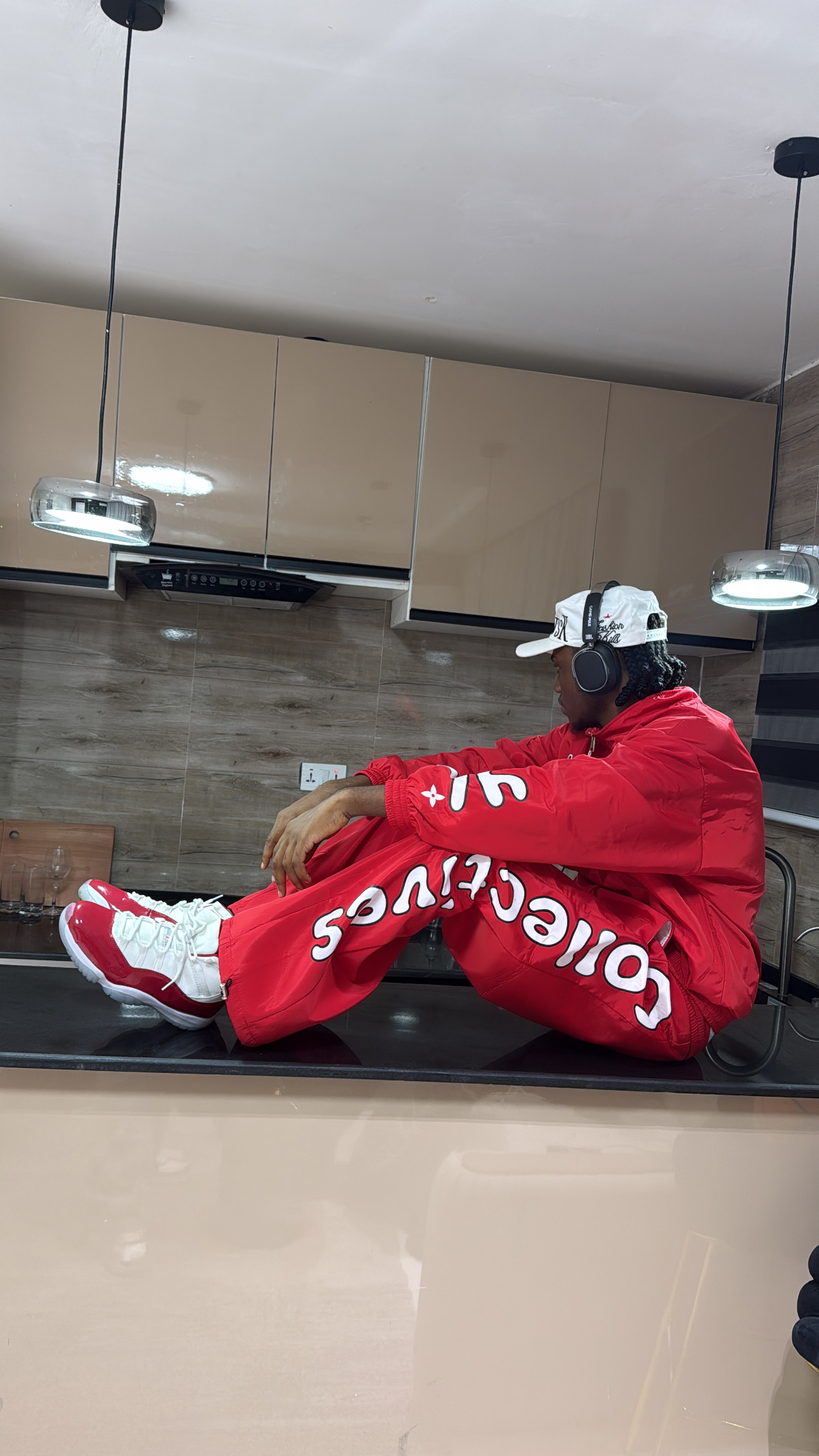 Nueldrick seated in a red tracksuit on a kitchen counter