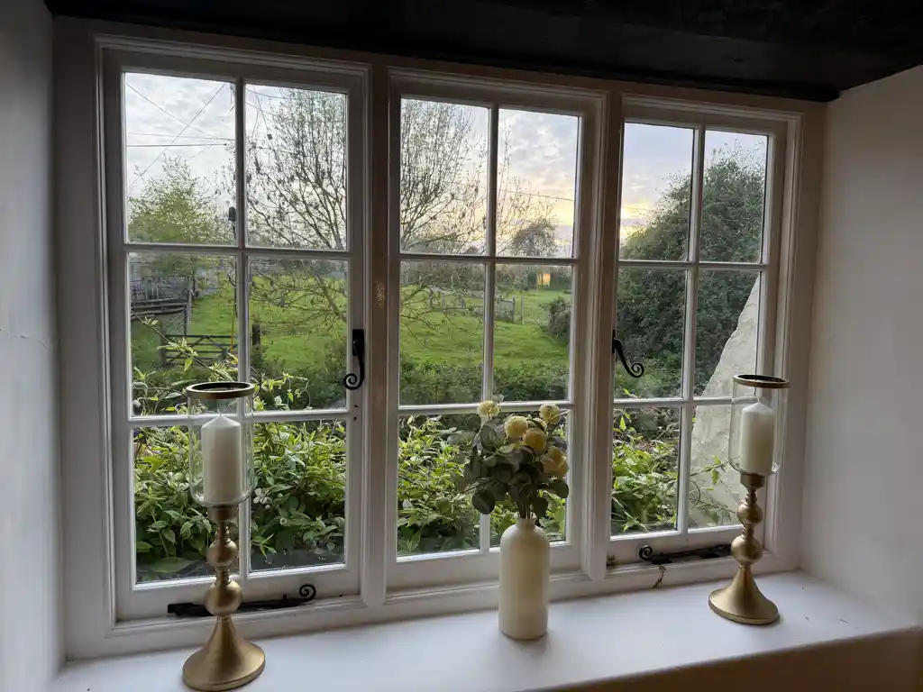Window view with brass candlesticks and flowers