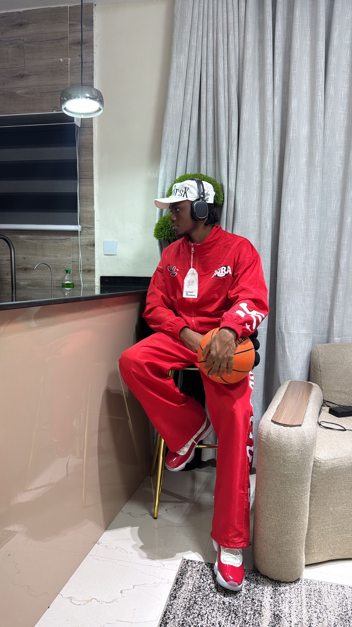 Nueldrick seated in a red tracksuit and headphones