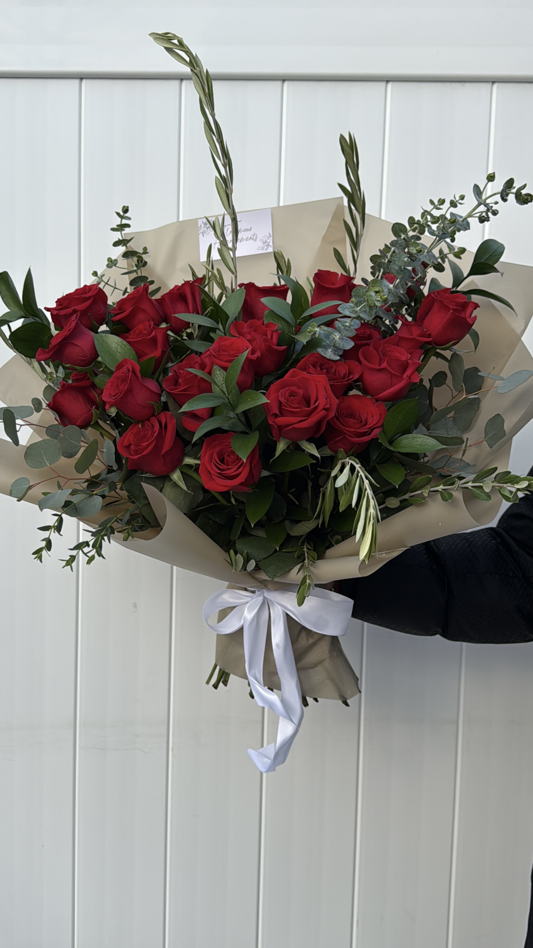 Large red rose bouquet with eucalyptus in kraft paper wrapping